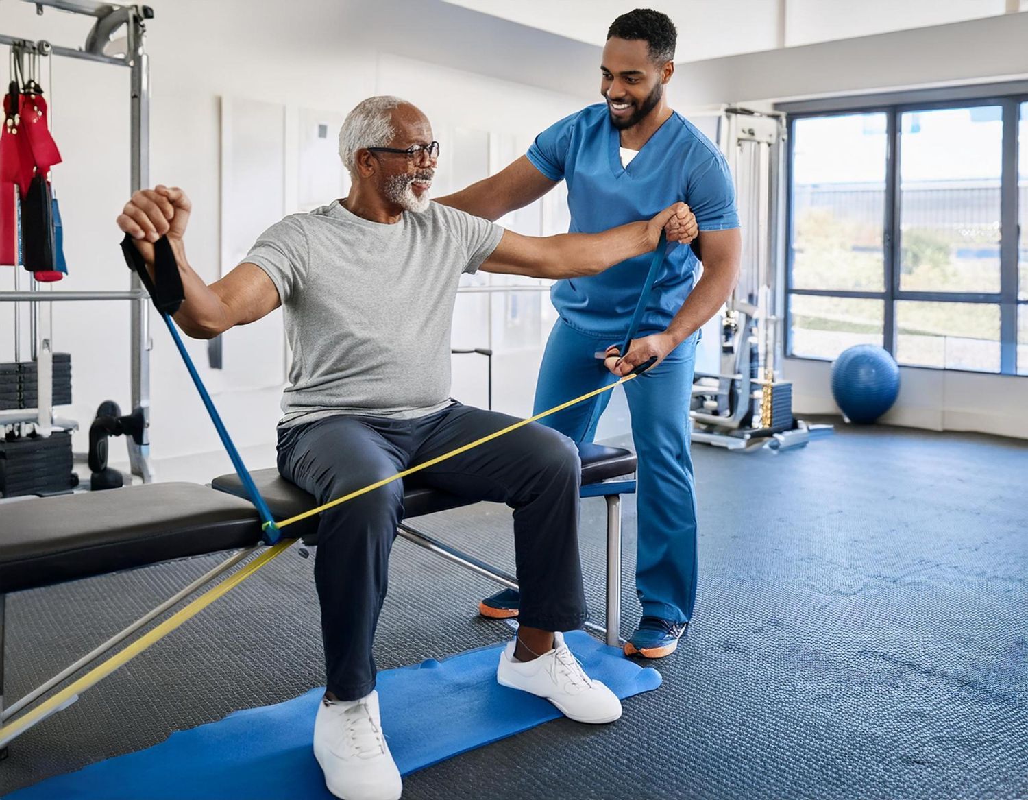 Therapist assisting a person with resistance band exercise in a gym. Both smiling.