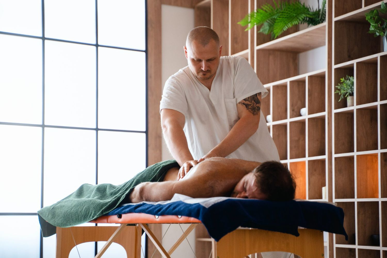 A man is getting a massage on a table in a room.