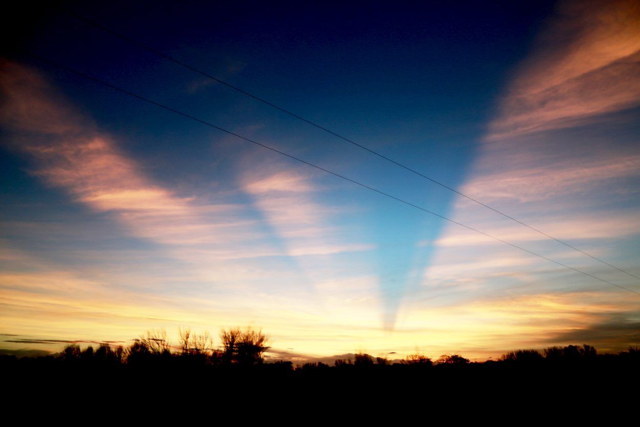 The sun is shining through the clouds at sunset