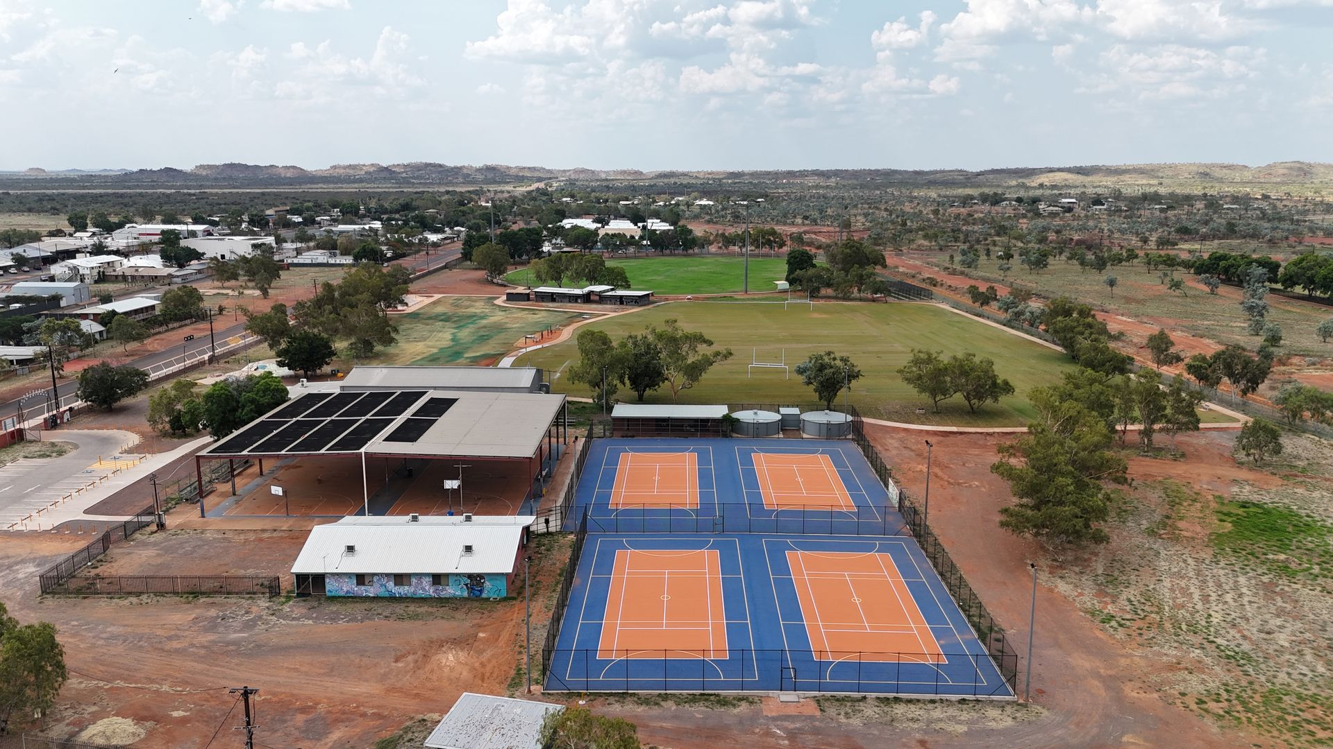 An aerial view of a tennis court in the middle of a field.