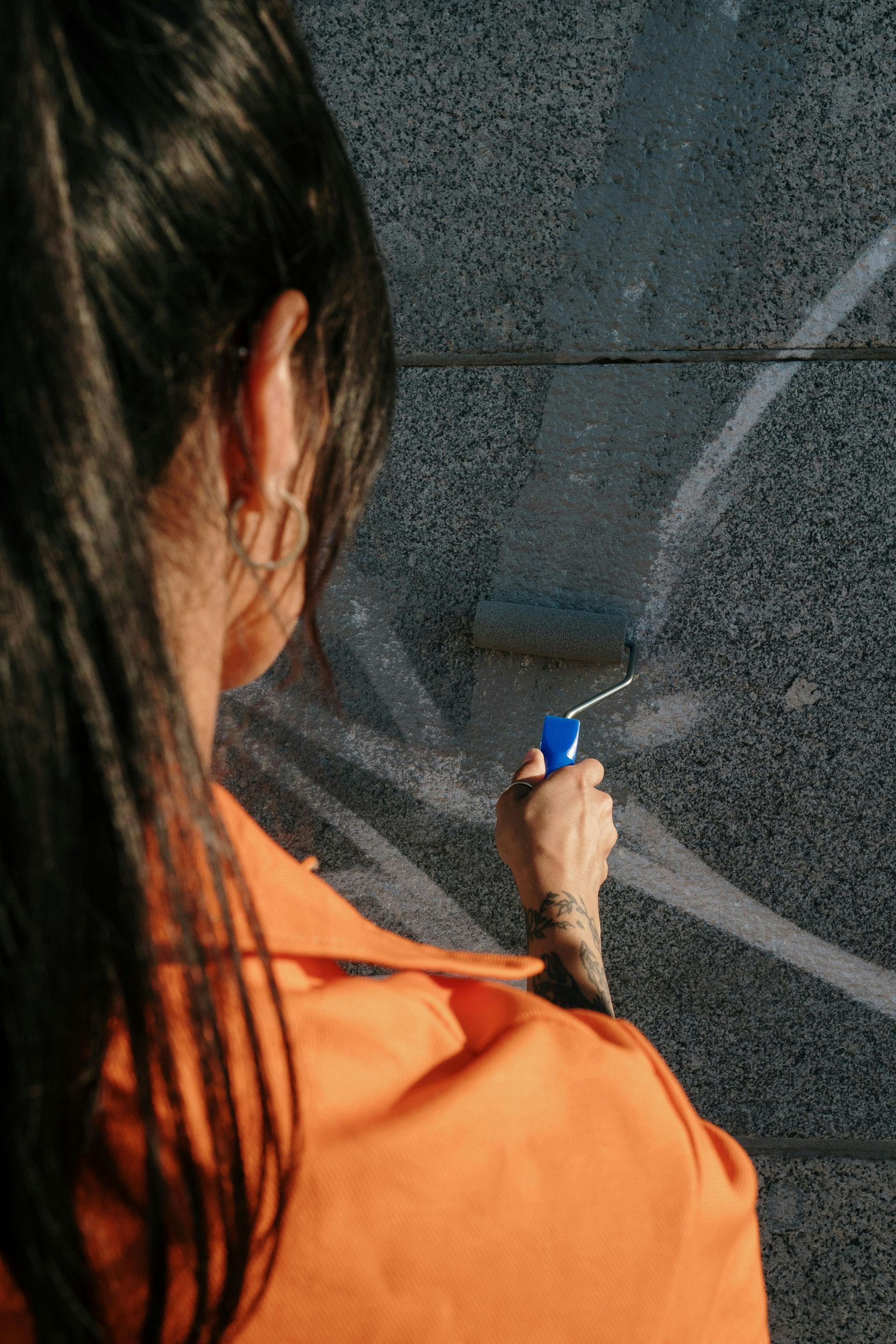 A woman is painting a wall with a roller.