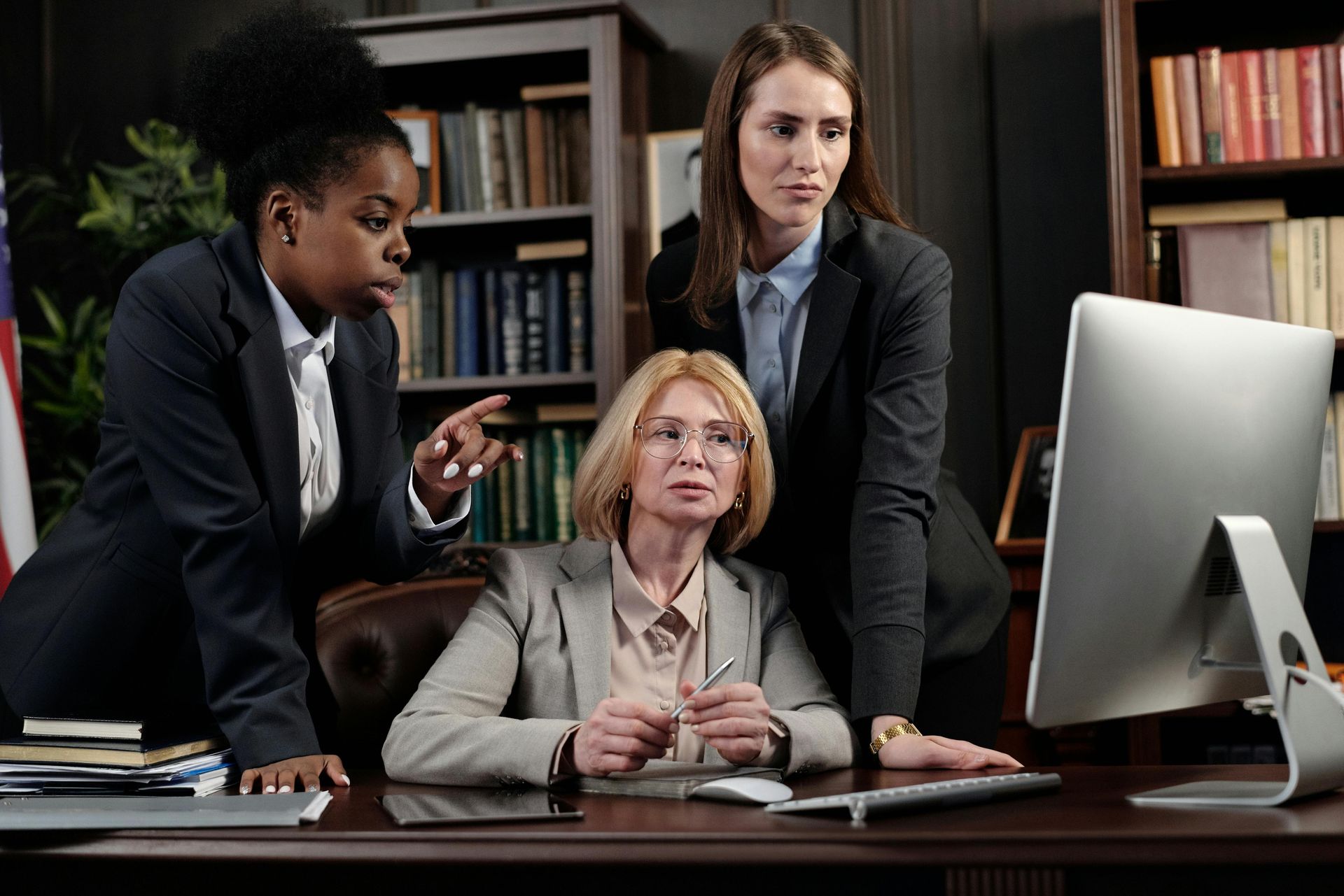 Four lawyers in suits pose in an office setting, with a 