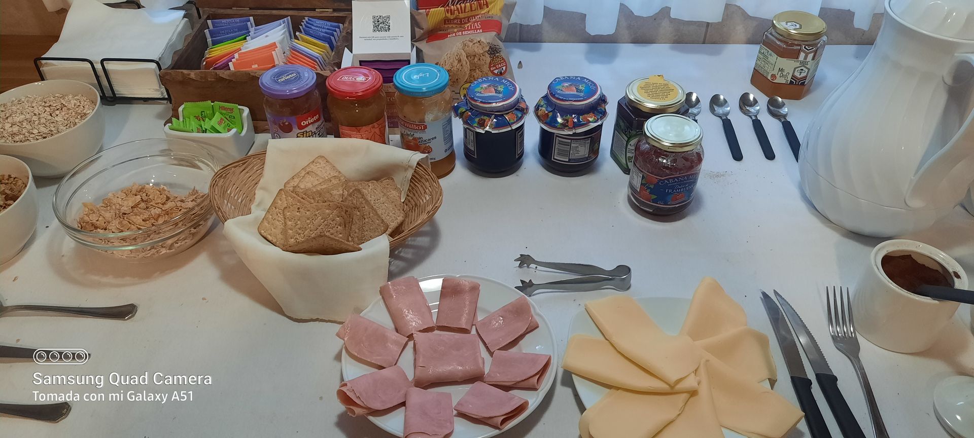 A table topped with plates of food and jars of jam.