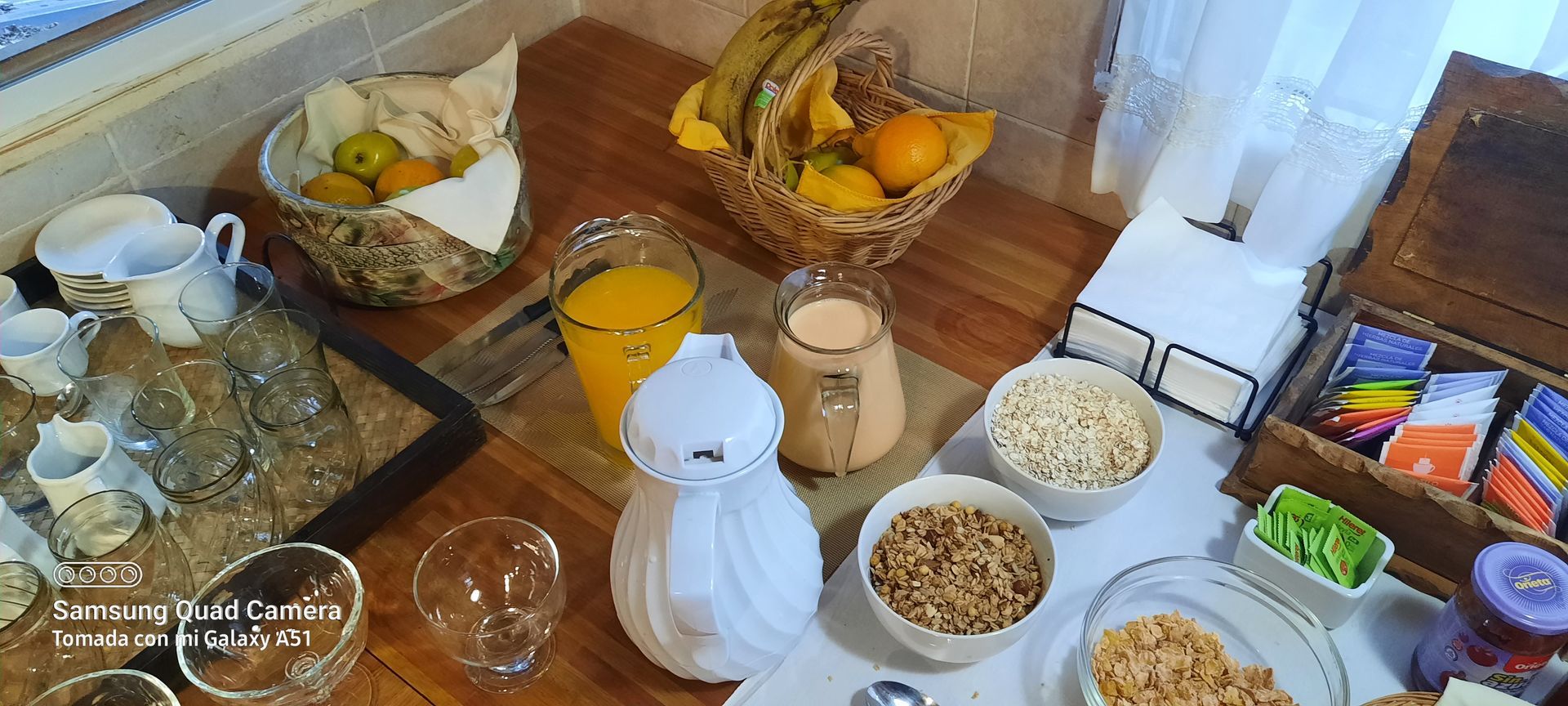 A wooden table topped with bowls of food and drinks.