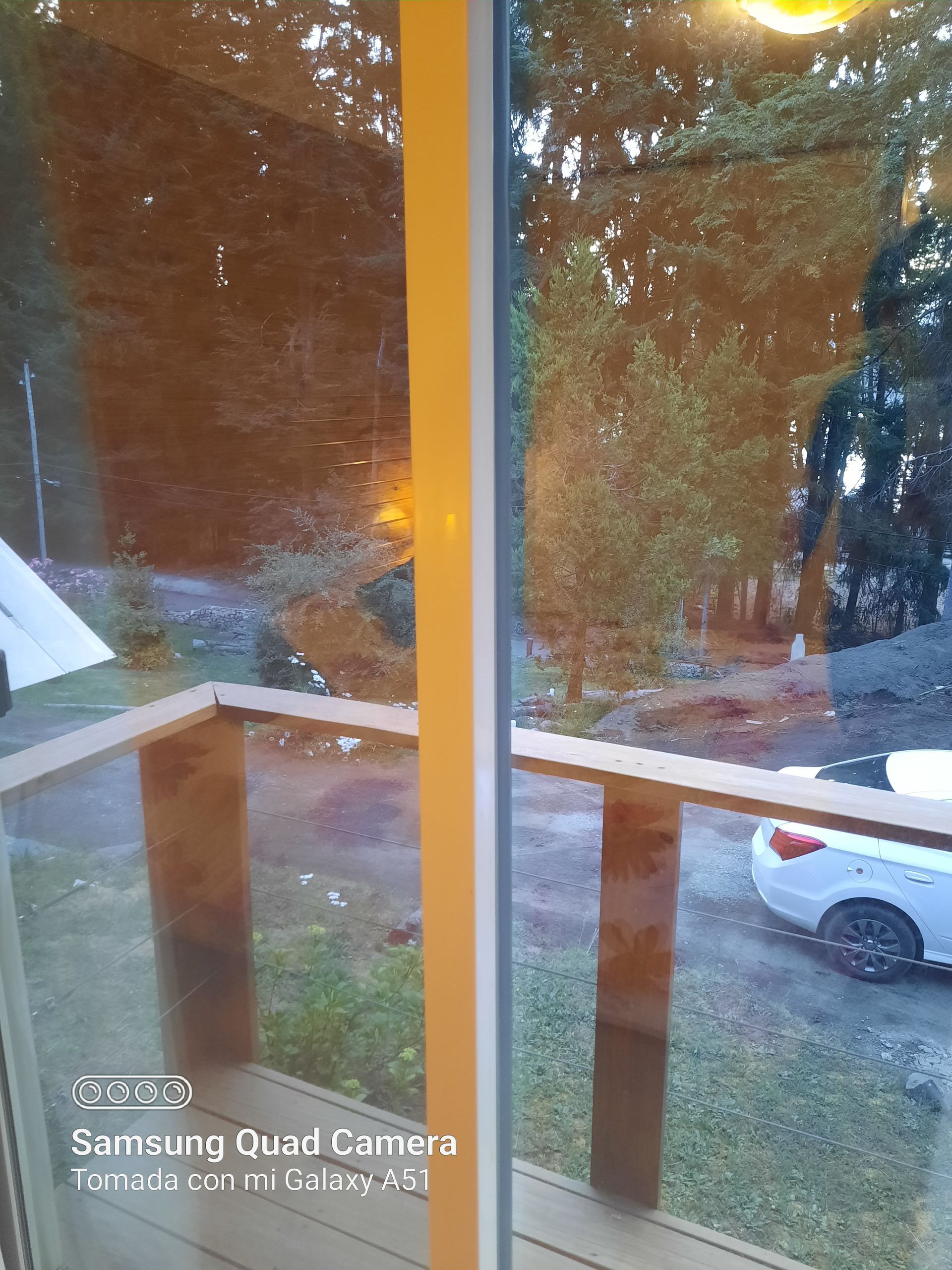A samsung quad camera took a picture of a car parked in front of a window.