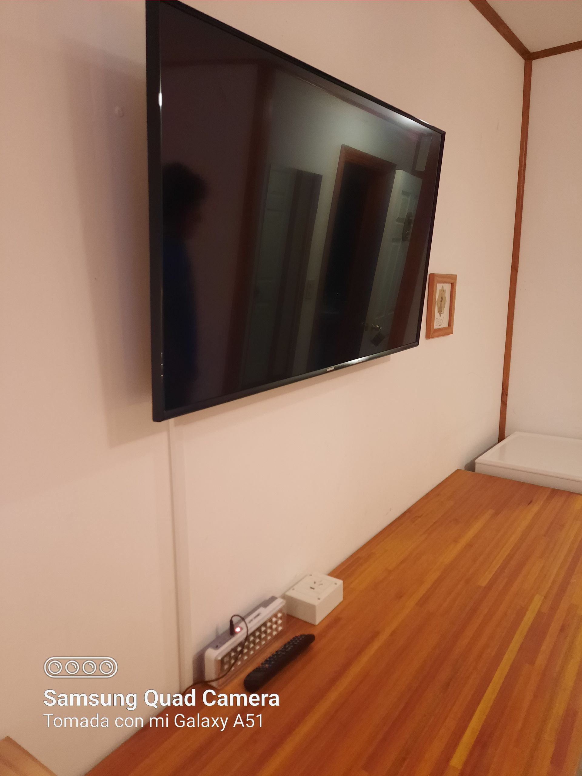 A samsung quad camera took a picture of a flat screen tv mounted on a wall.