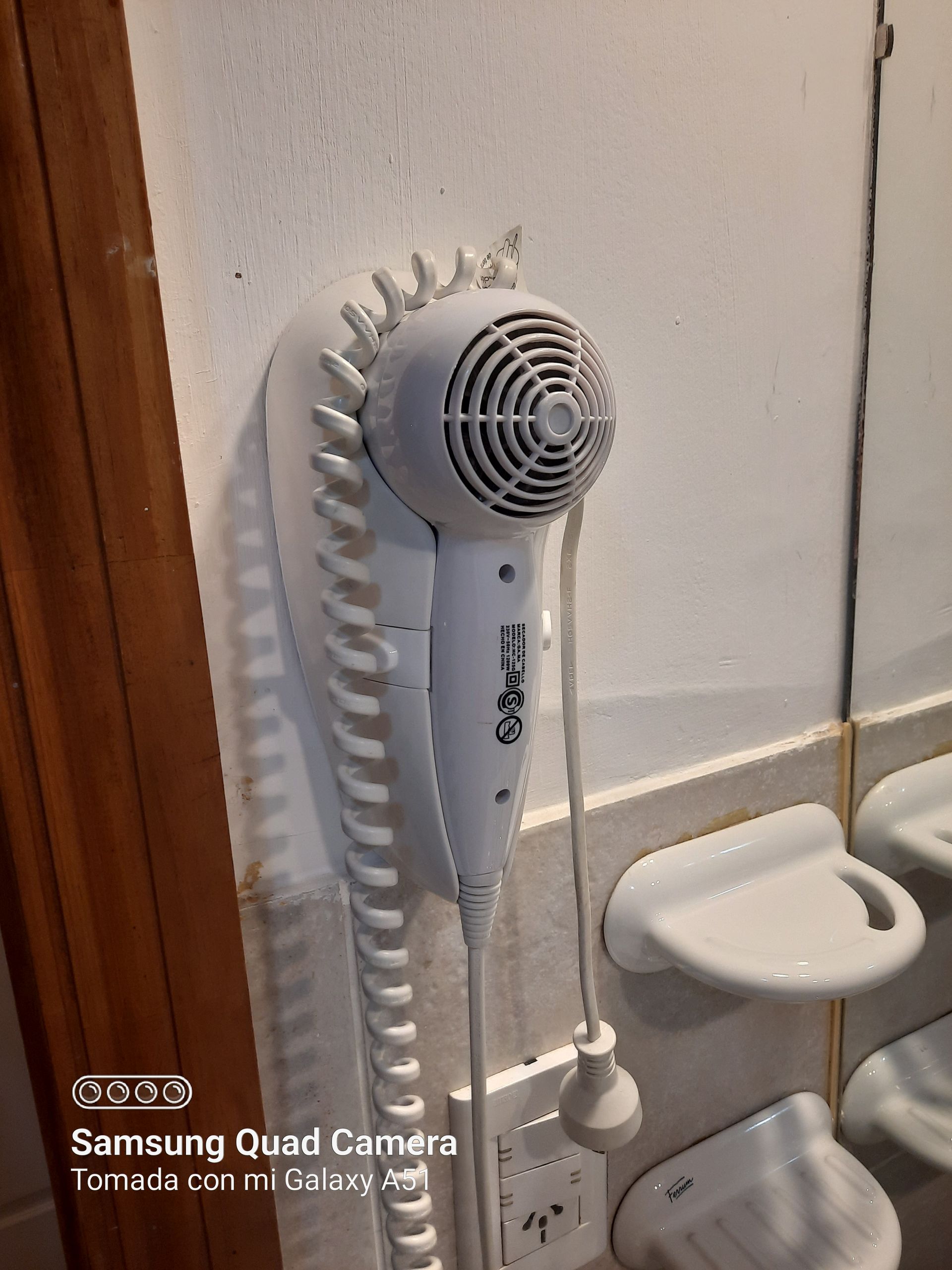 A hair dryer is hanging on a wall in a bathroom.