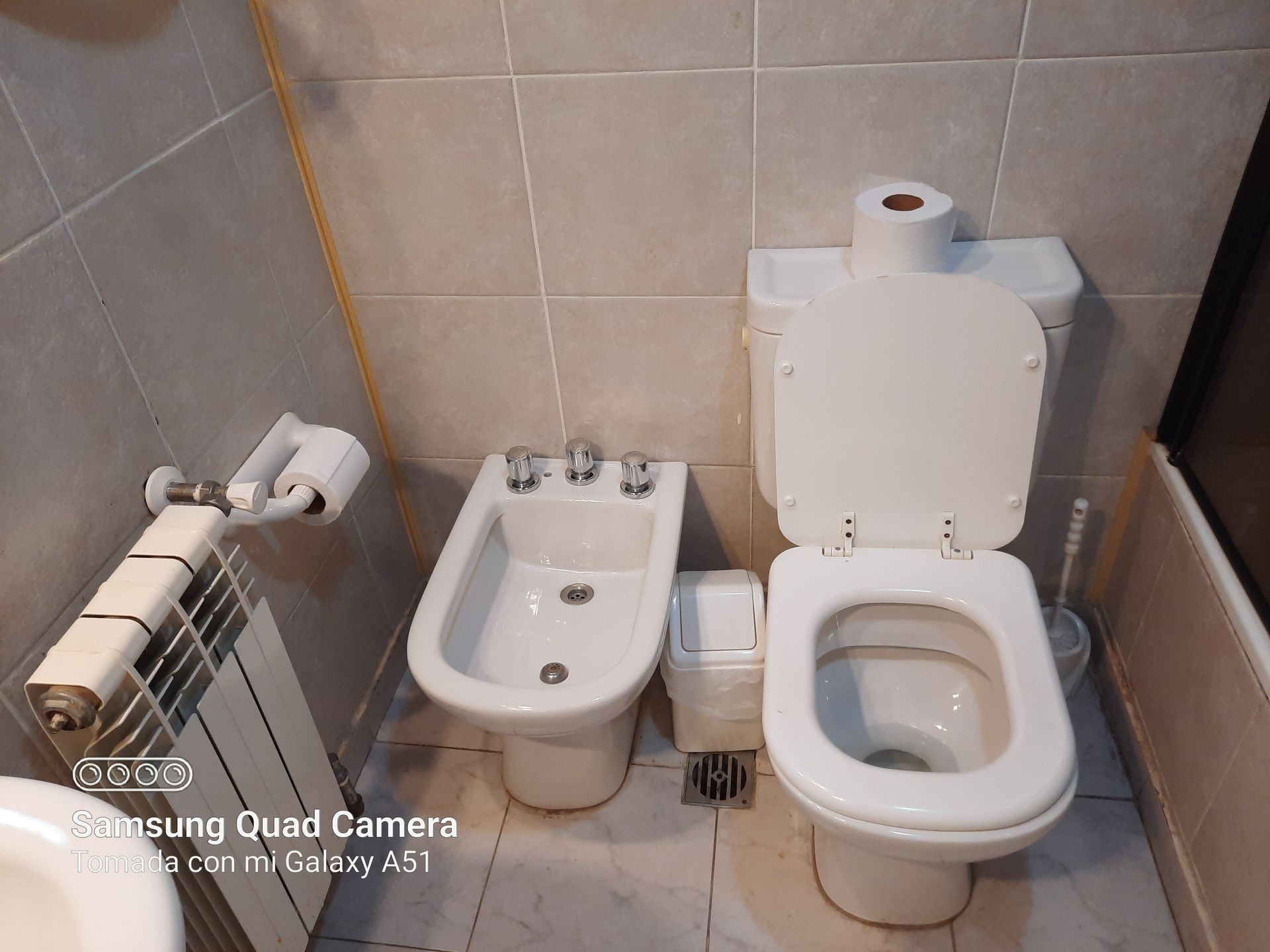 A bathroom with two toilets and a bidet