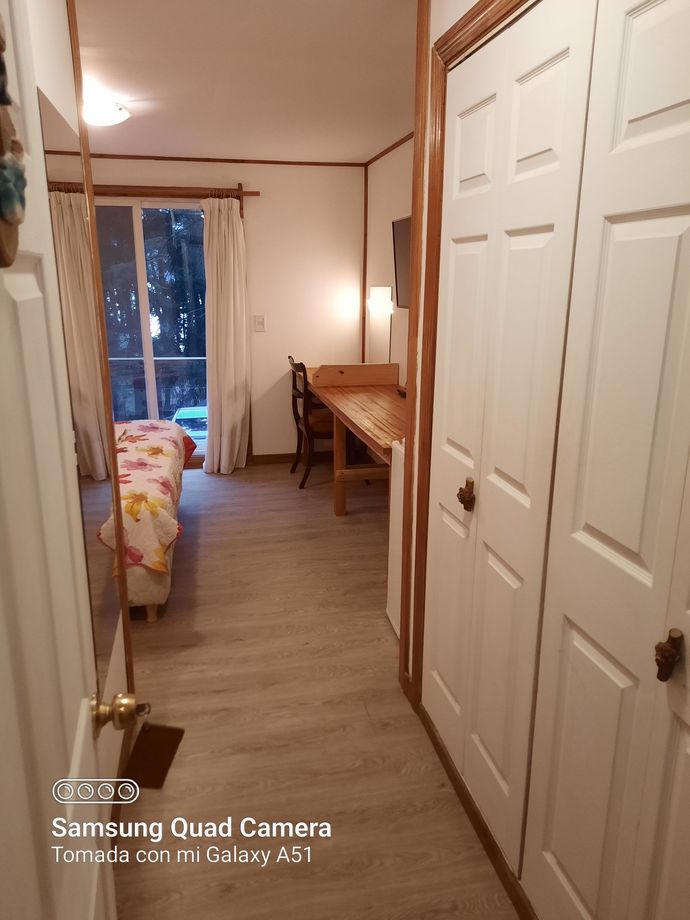 A bedroom with a bed , desk , and closets taken by a samsung quad camera