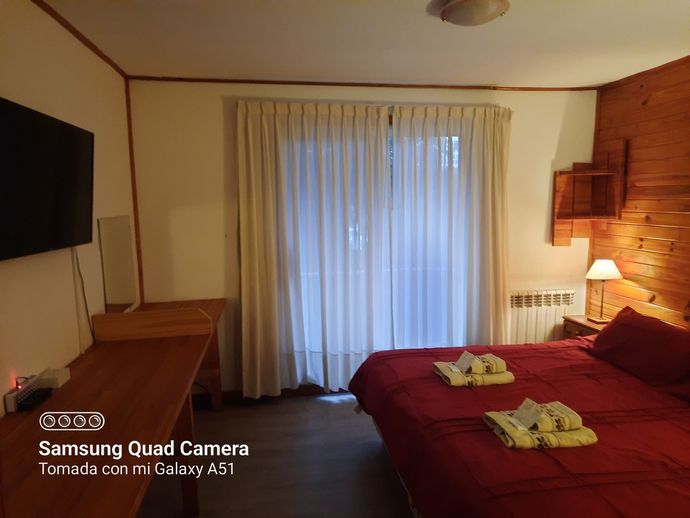 A bedroom with a bed , television , and sliding glass doors.