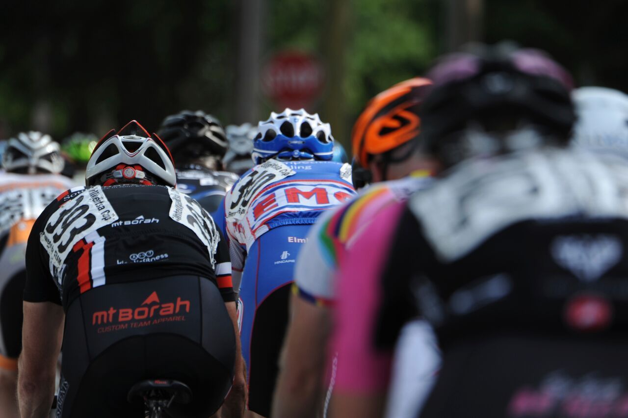 A group of cyclists are riding down a road and one of them is wearing a shirt that says maorah