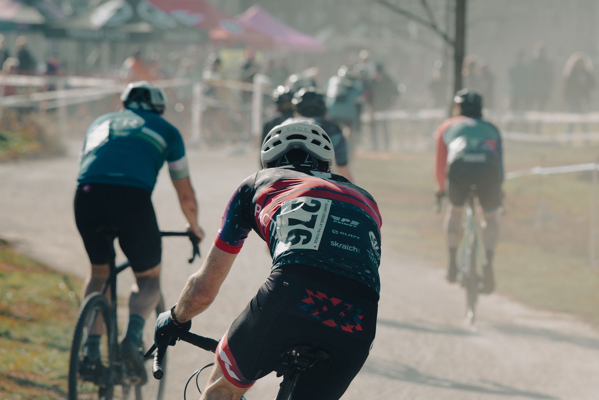 A group of cyclists are riding down a dirt road.