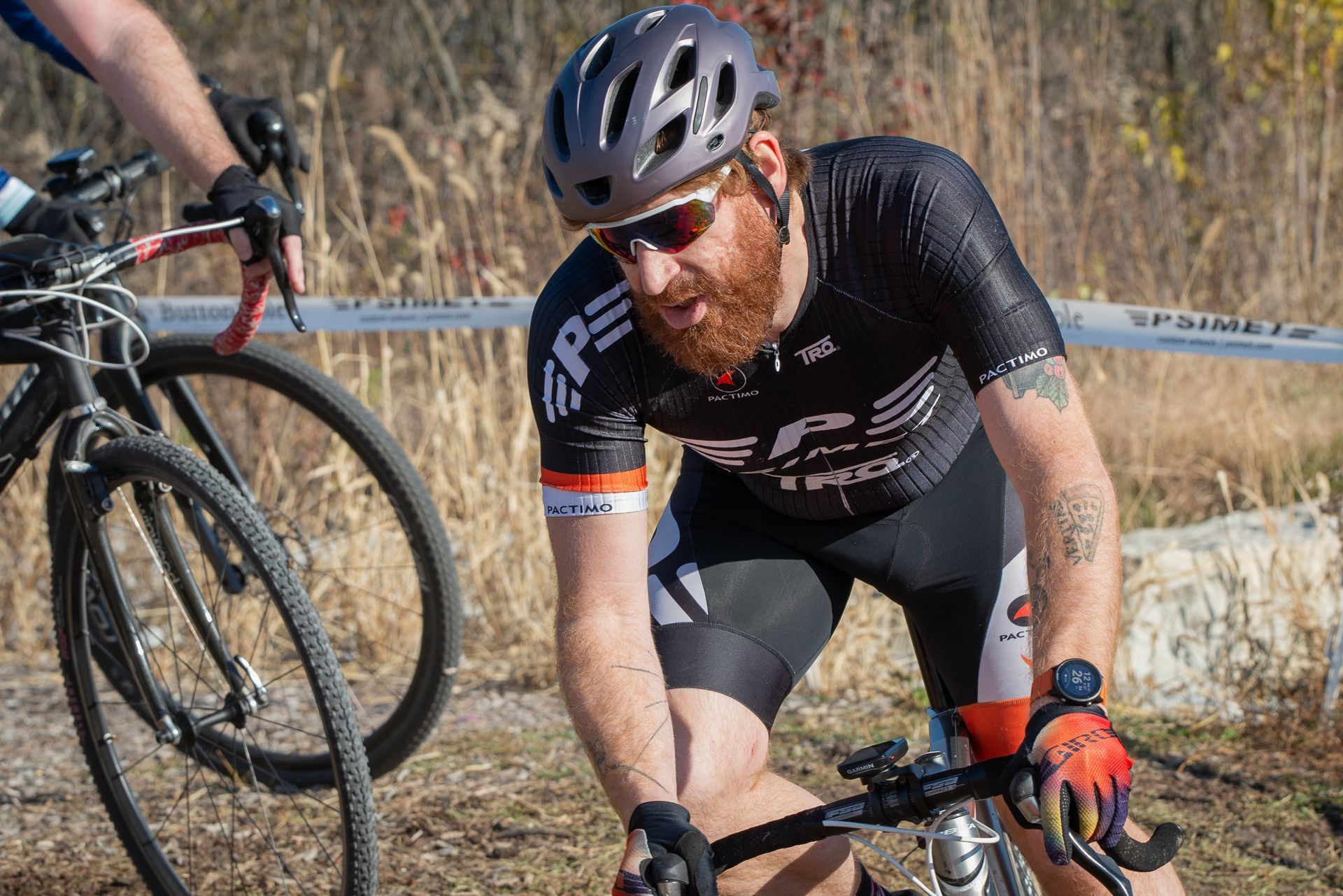 A man with a beard is riding a bike on a dirt road.