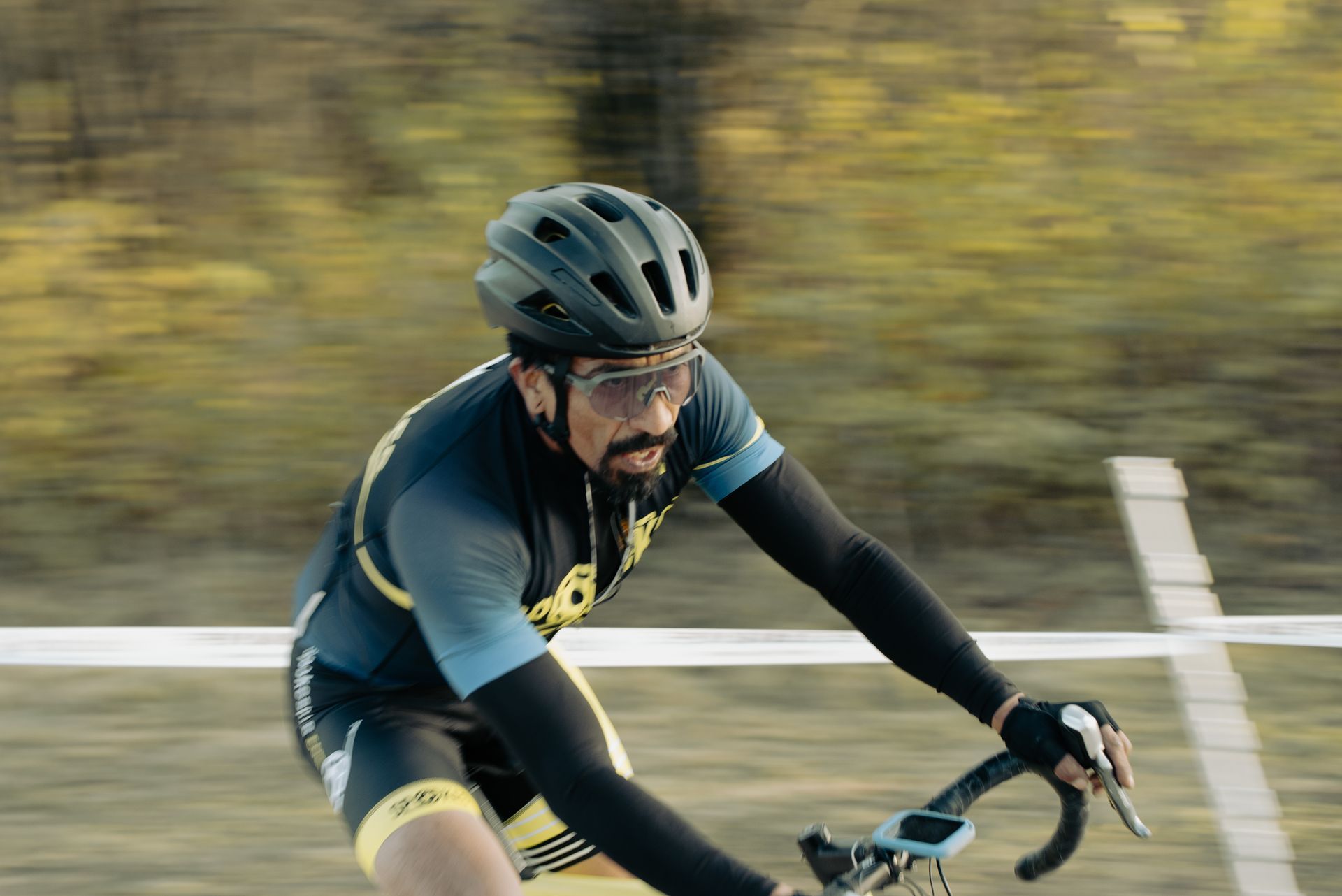 A man wearing a helmet and sunglasses is riding a bike on a road.