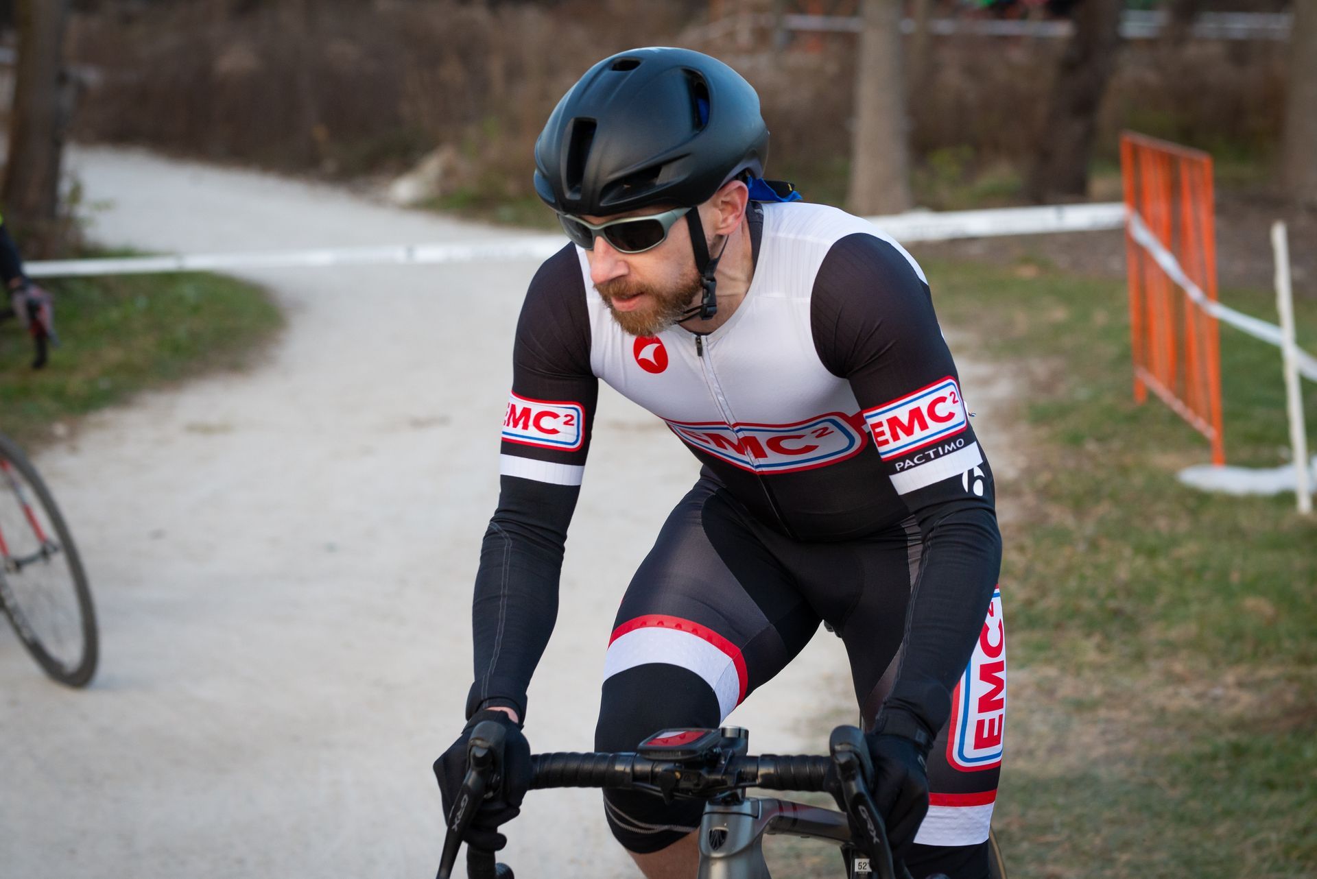 A man wearing a helmet and sunglasses is riding a bike on a dirt road.