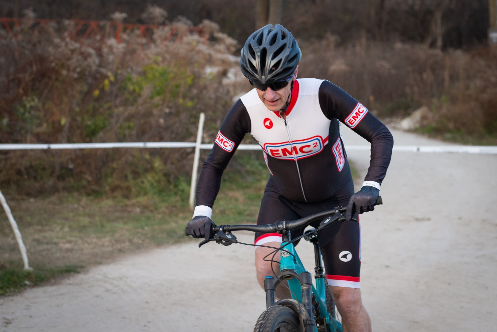 A man is riding a bike down a dirt road.