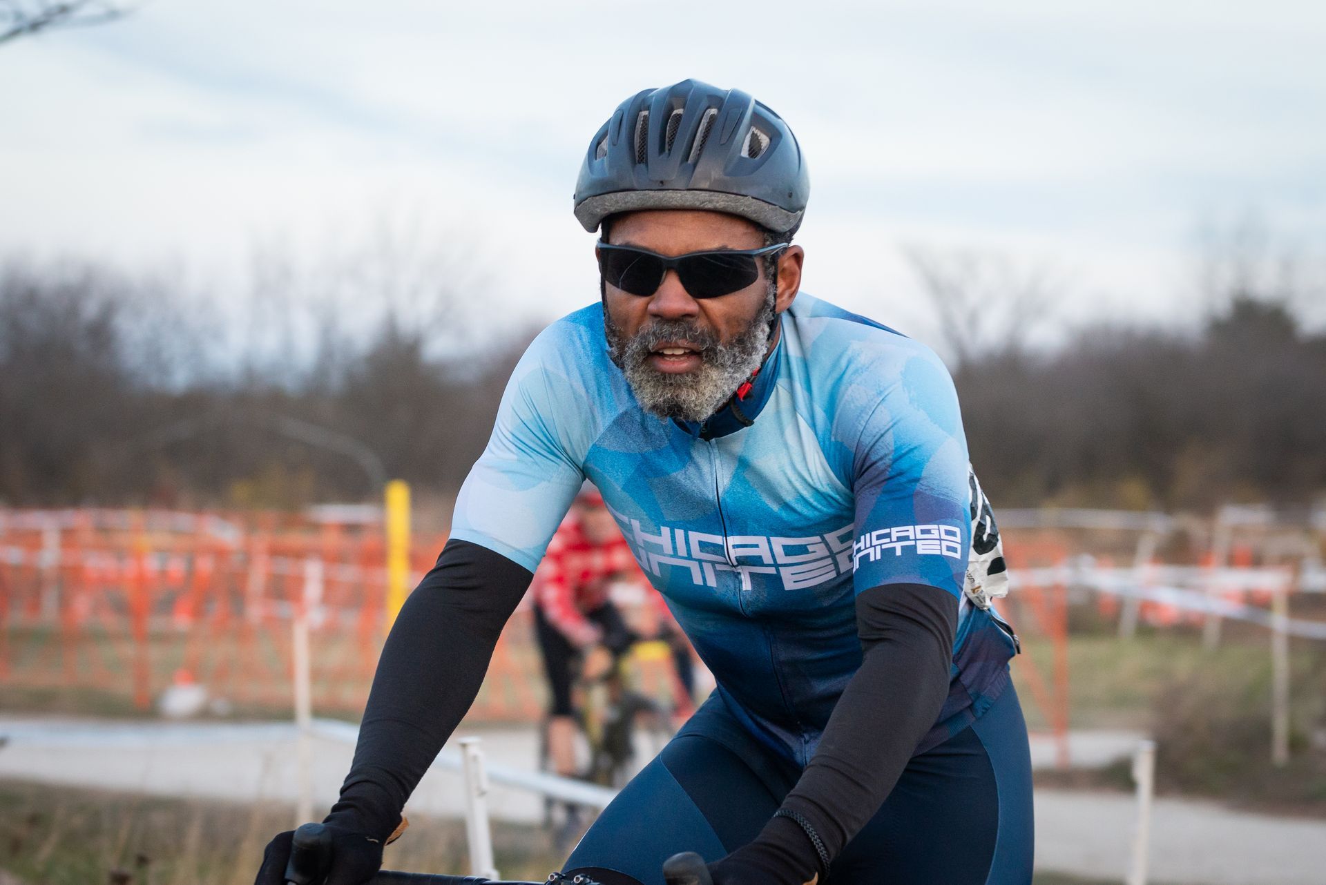 A man wearing a helmet and sunglasses is riding a bike.