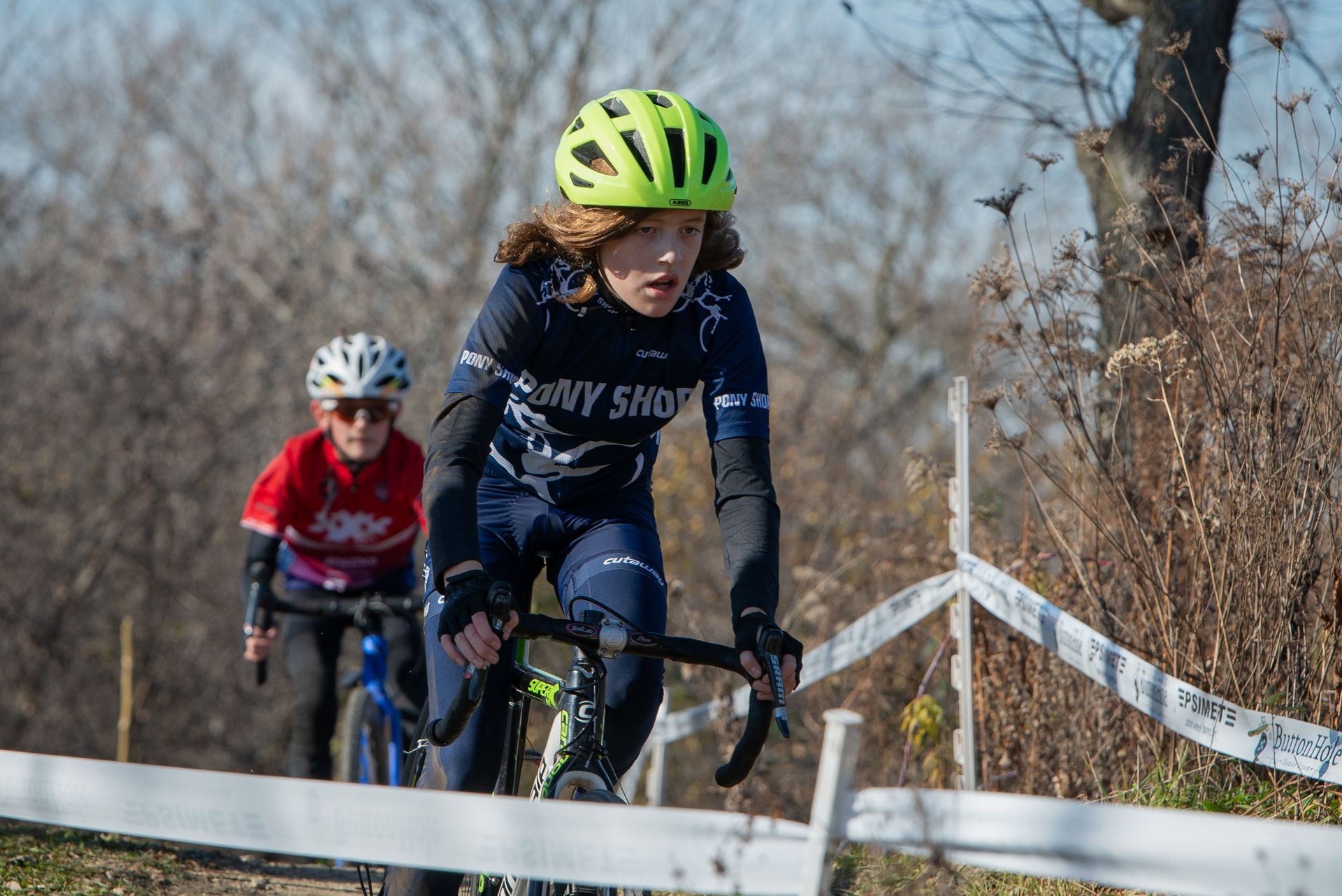 A woman wearing a yellow helmet is riding a bike down a hill.