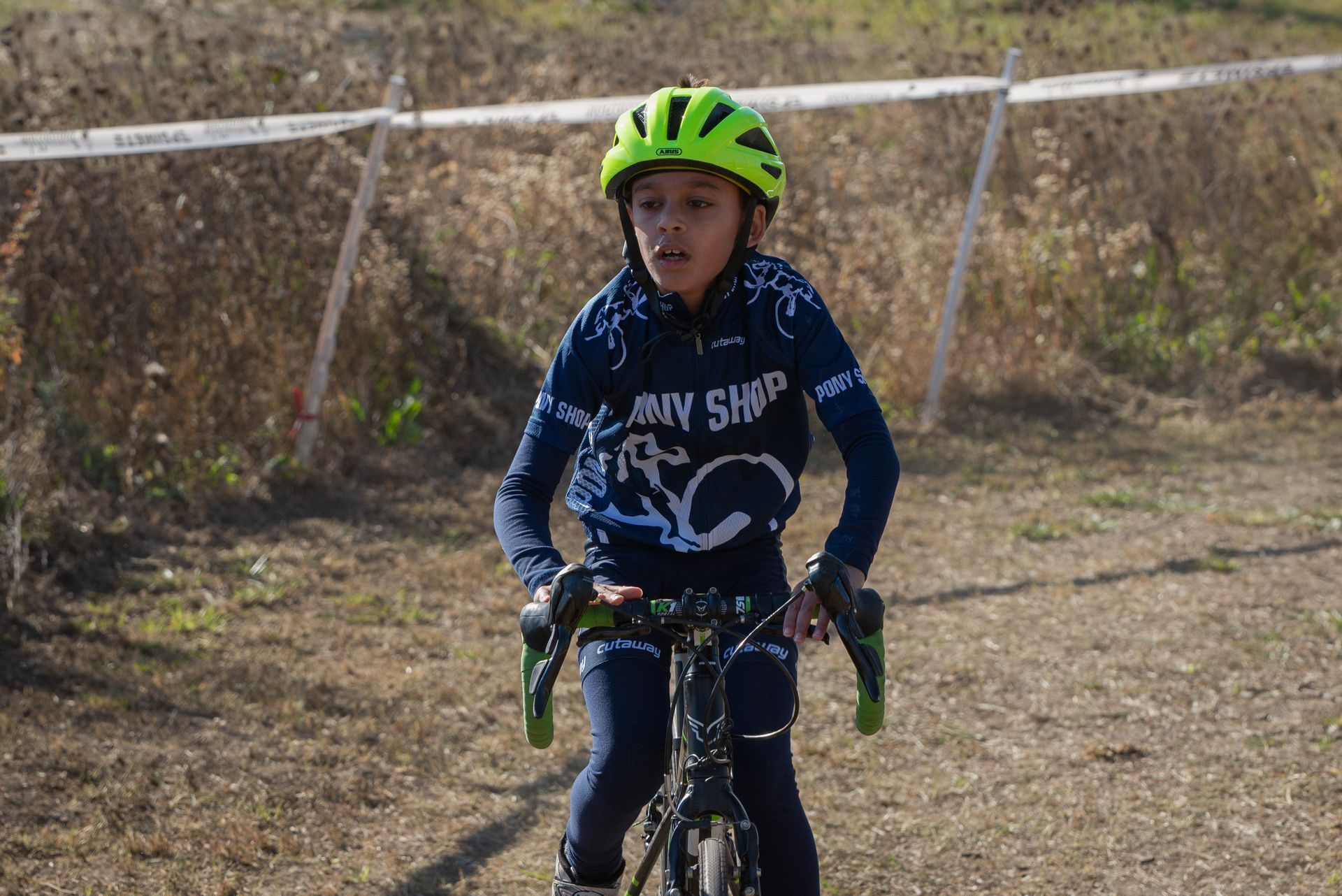 A young boy wearing a helmet is riding a bike on a dirt road.