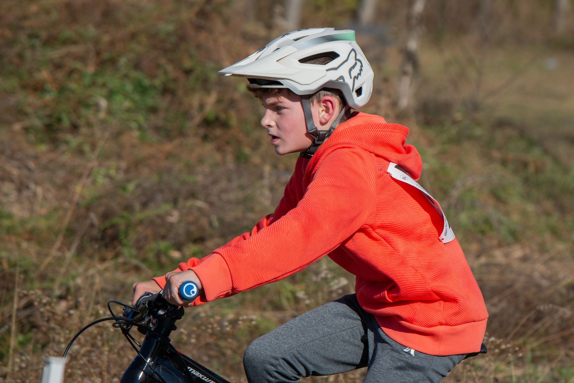 A young boy wearing a helmet is riding a bike.