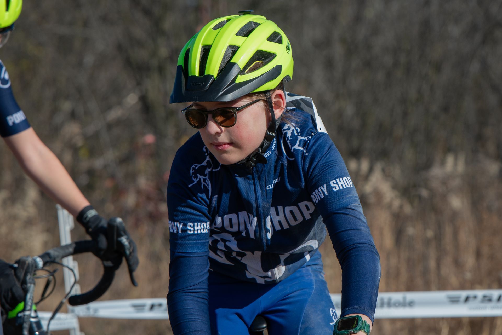 A young boy wearing a helmet and sunglasses is riding a bike.