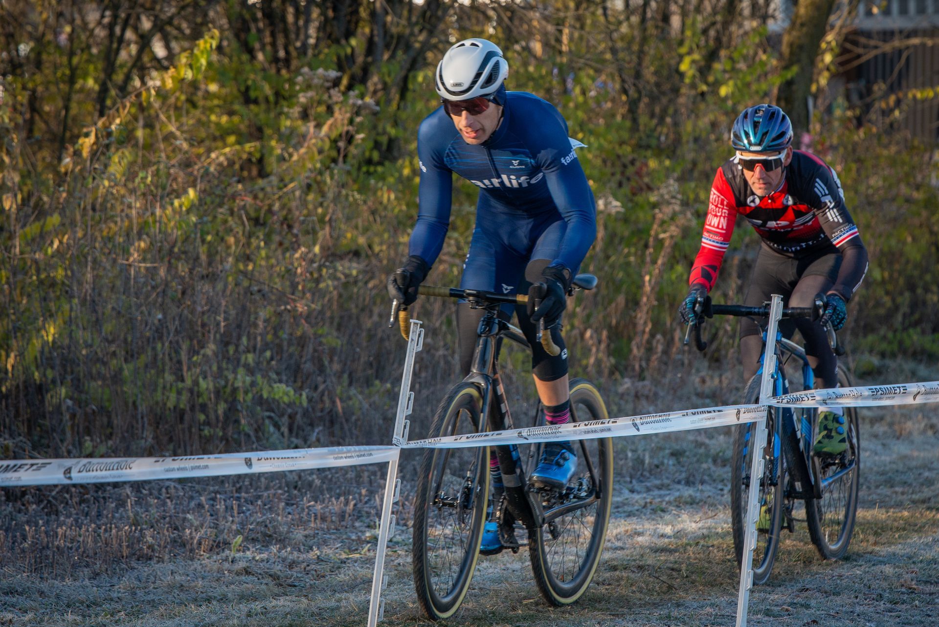 Two men are riding bicycles on a dirt road.