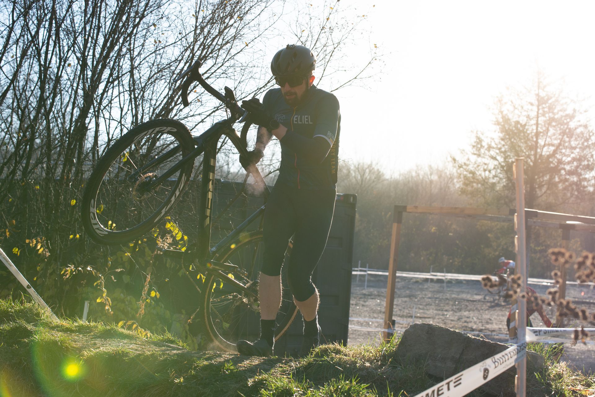 A man is standing next to a bicycle on top of a dirt hill.