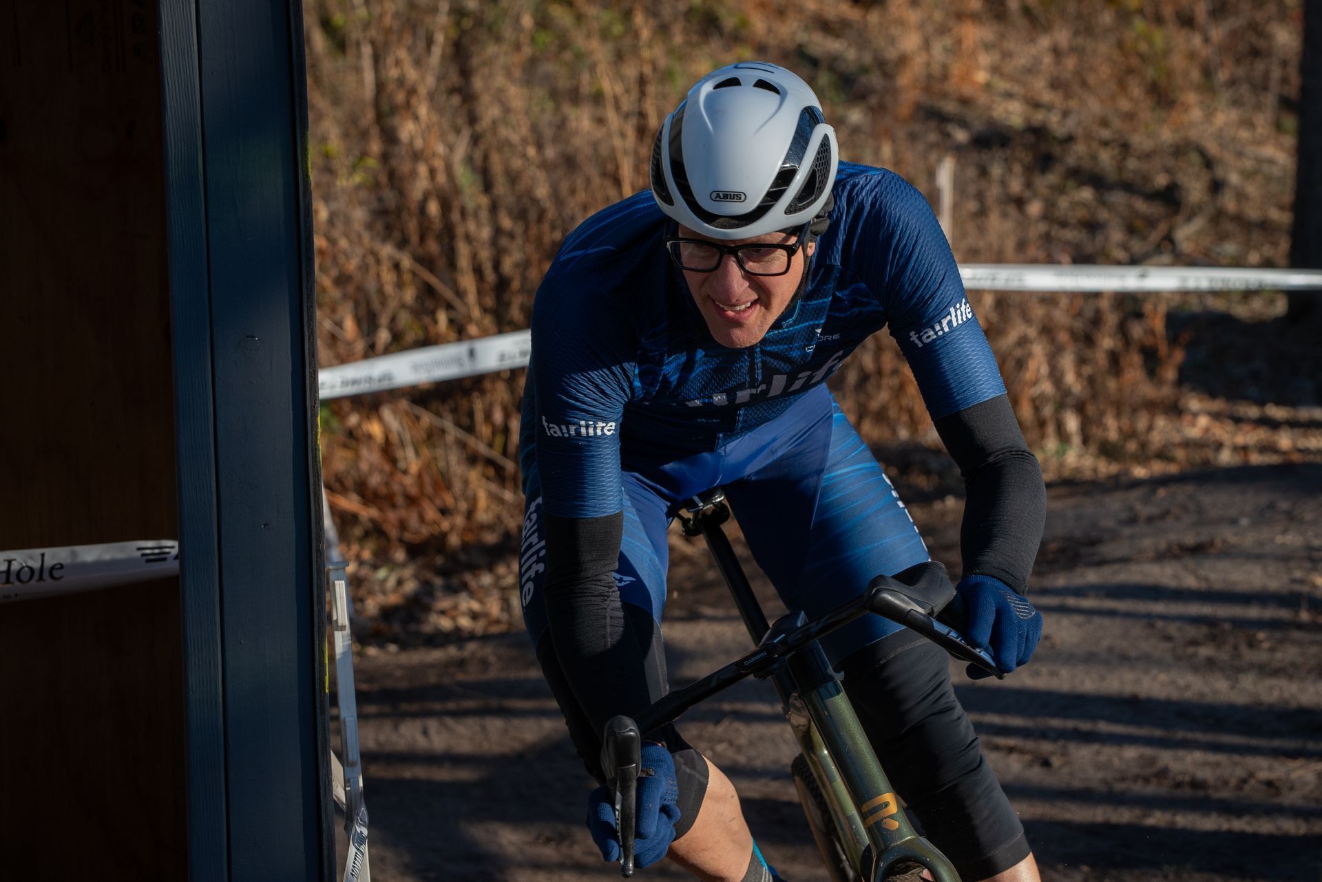 A man wearing a helmet and glasses is riding a bike on a dirt road.