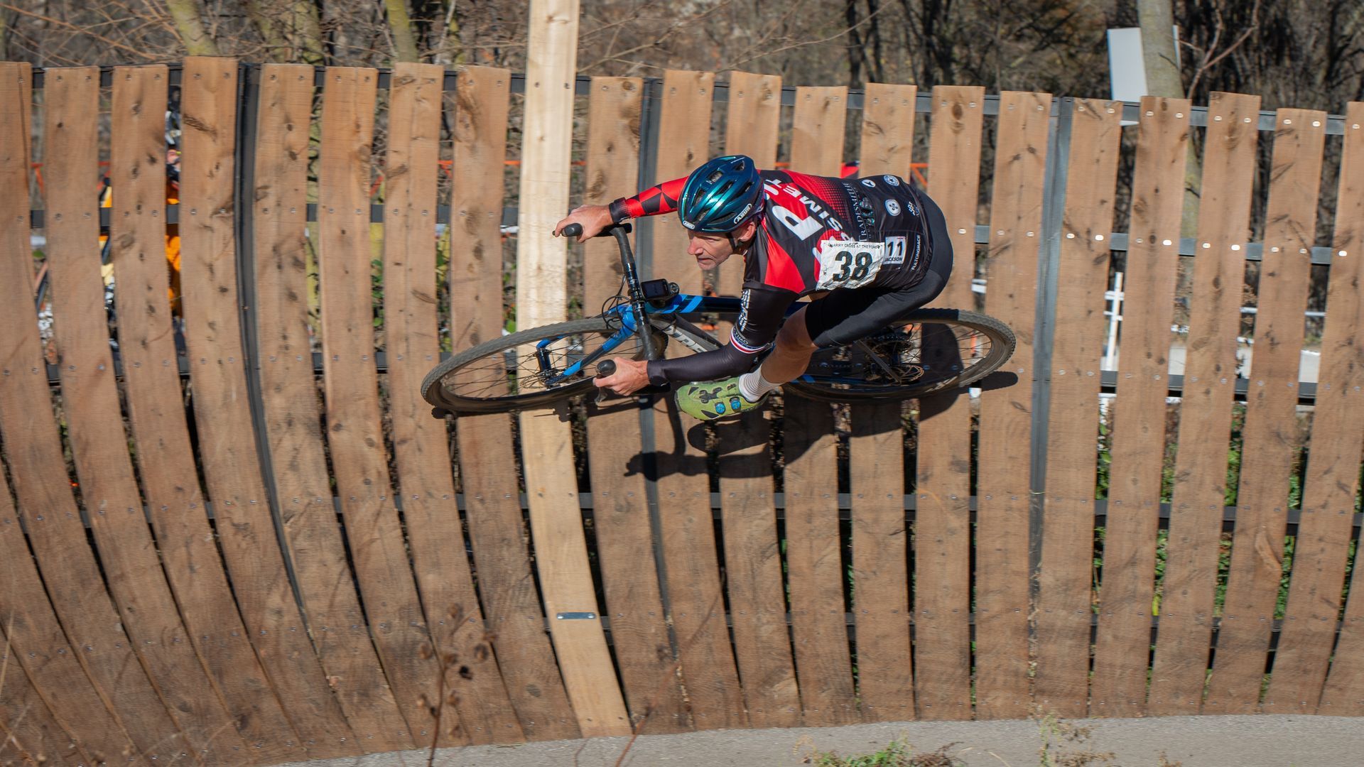 A man is riding a bike over a wooden fence.