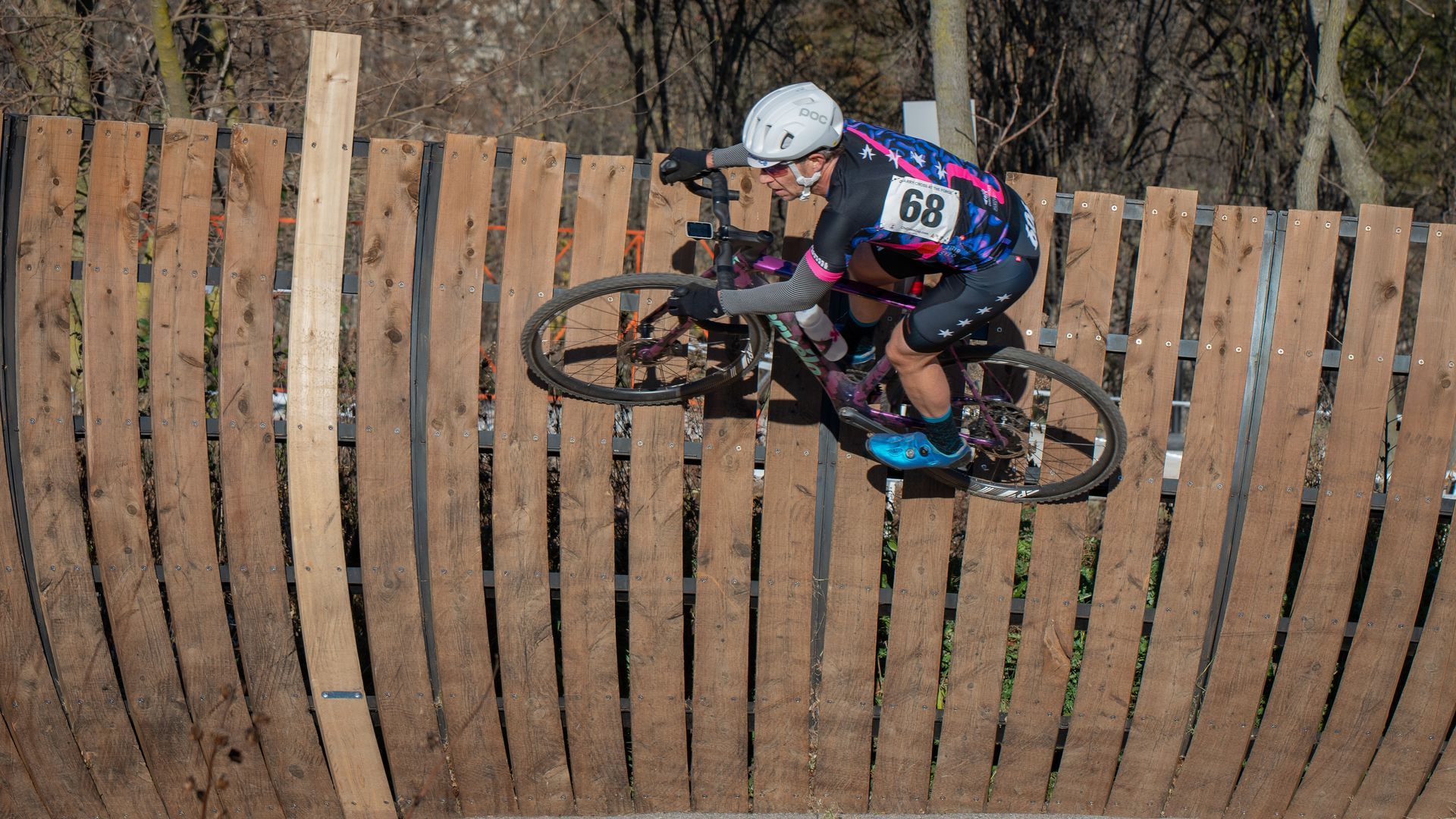 A person is riding a bike over a wooden fence.
