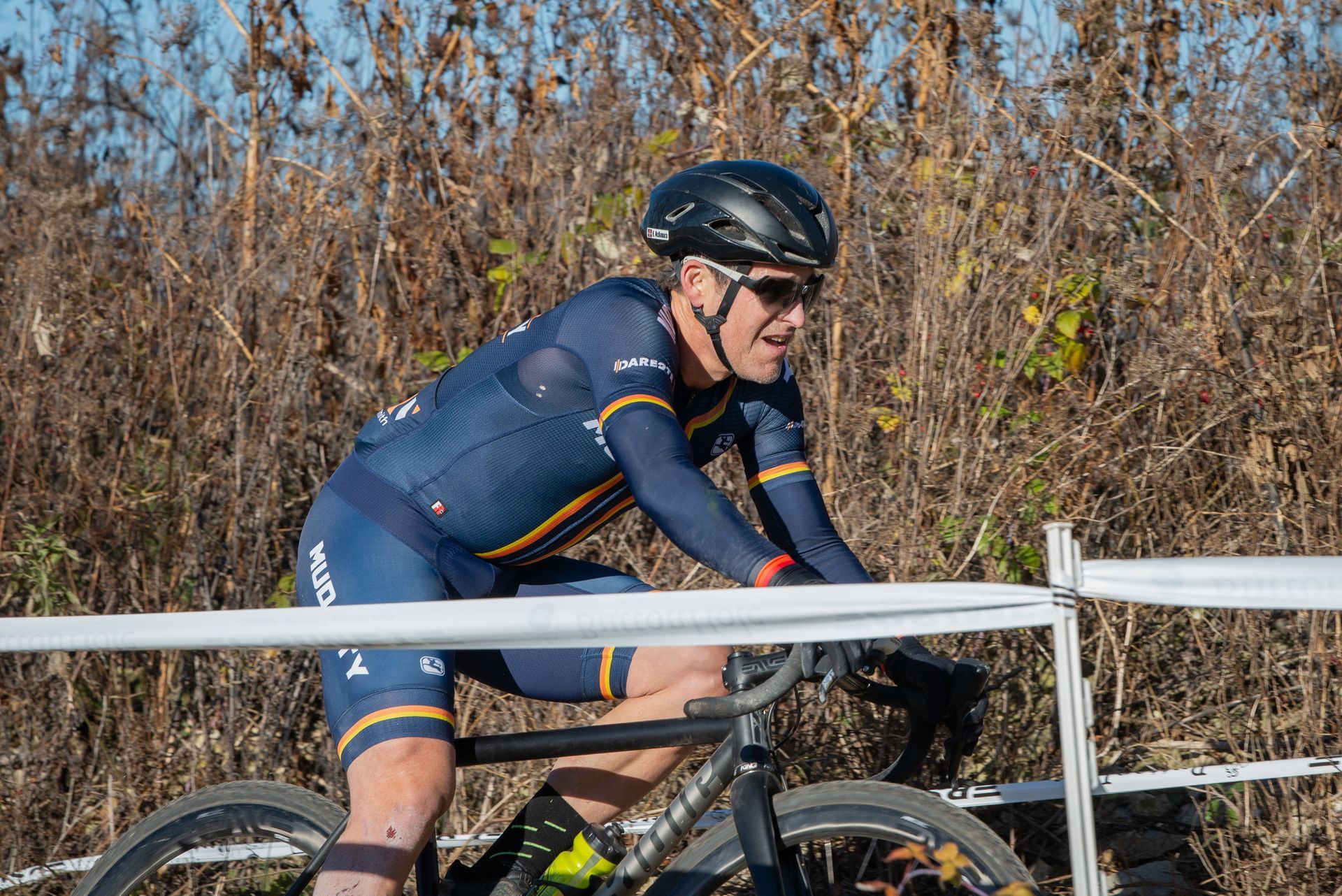 A man wearing a helmet and sunglasses is riding a bike.