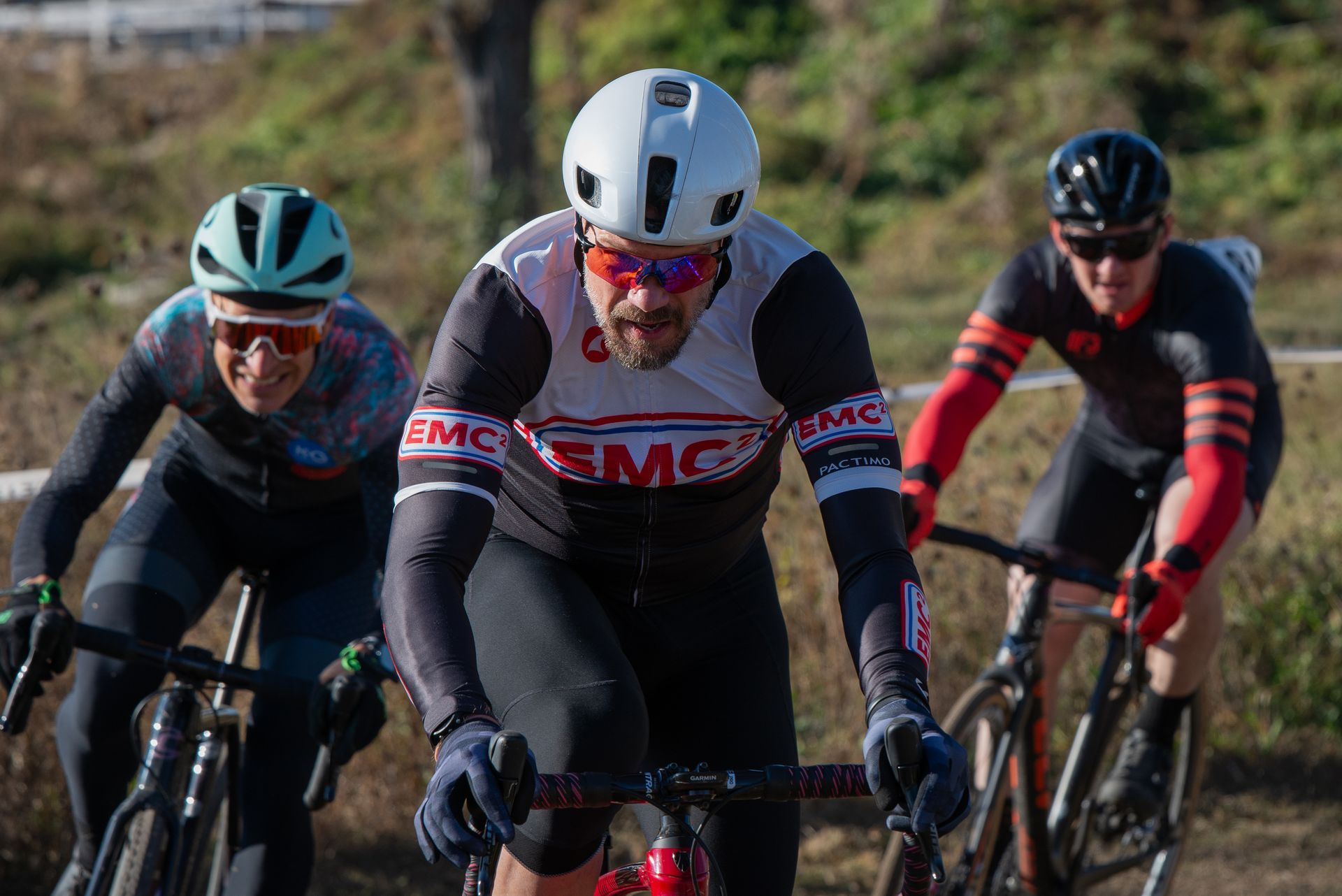 Three men are riding bicycles down a dirt road.