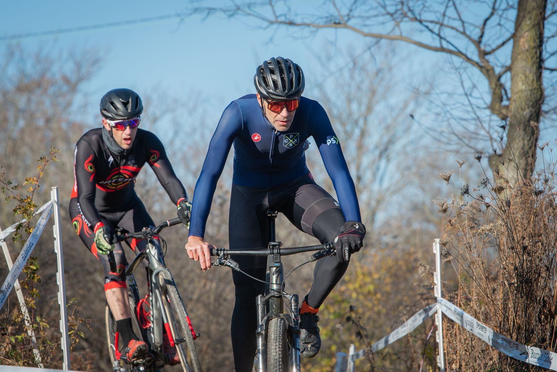Two men are riding bicycles on a dirt road.