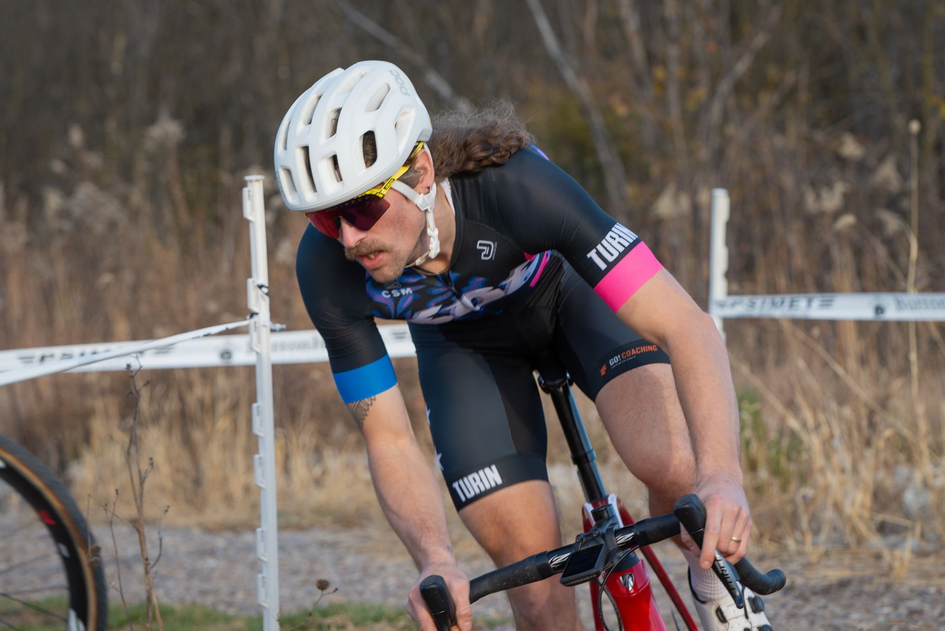 A man wearing a helmet and sunglasses is riding a bike on a dirt road.