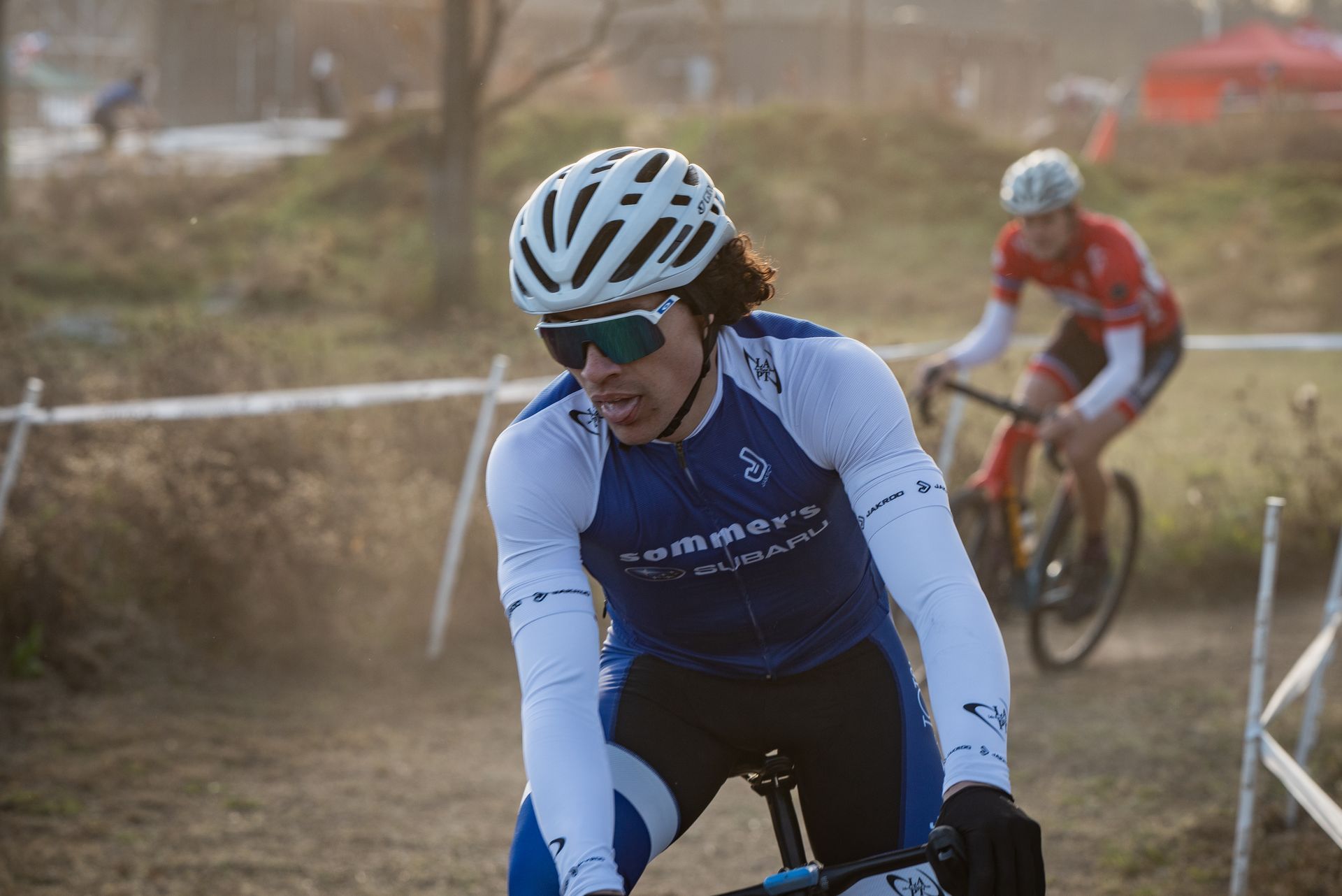 A man wearing a helmet and sunglasses is riding a bike on a dirt road.