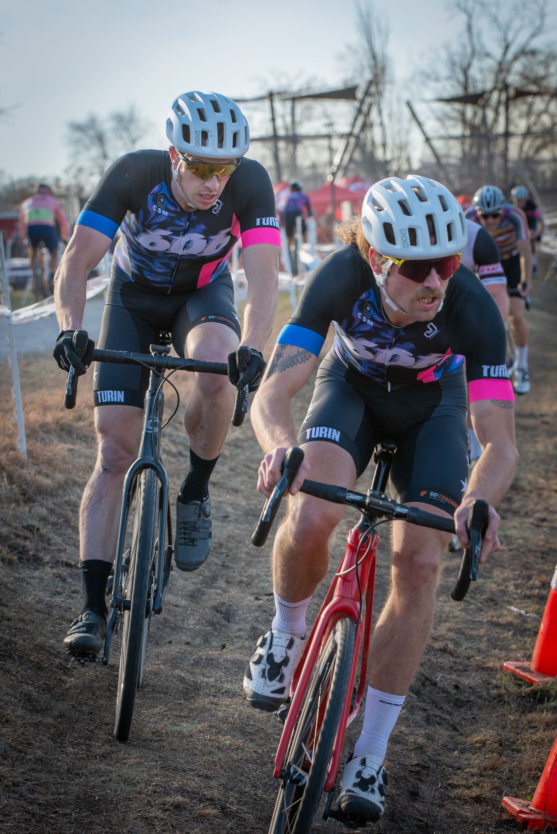 Two men are riding bicycles on a dirt road.