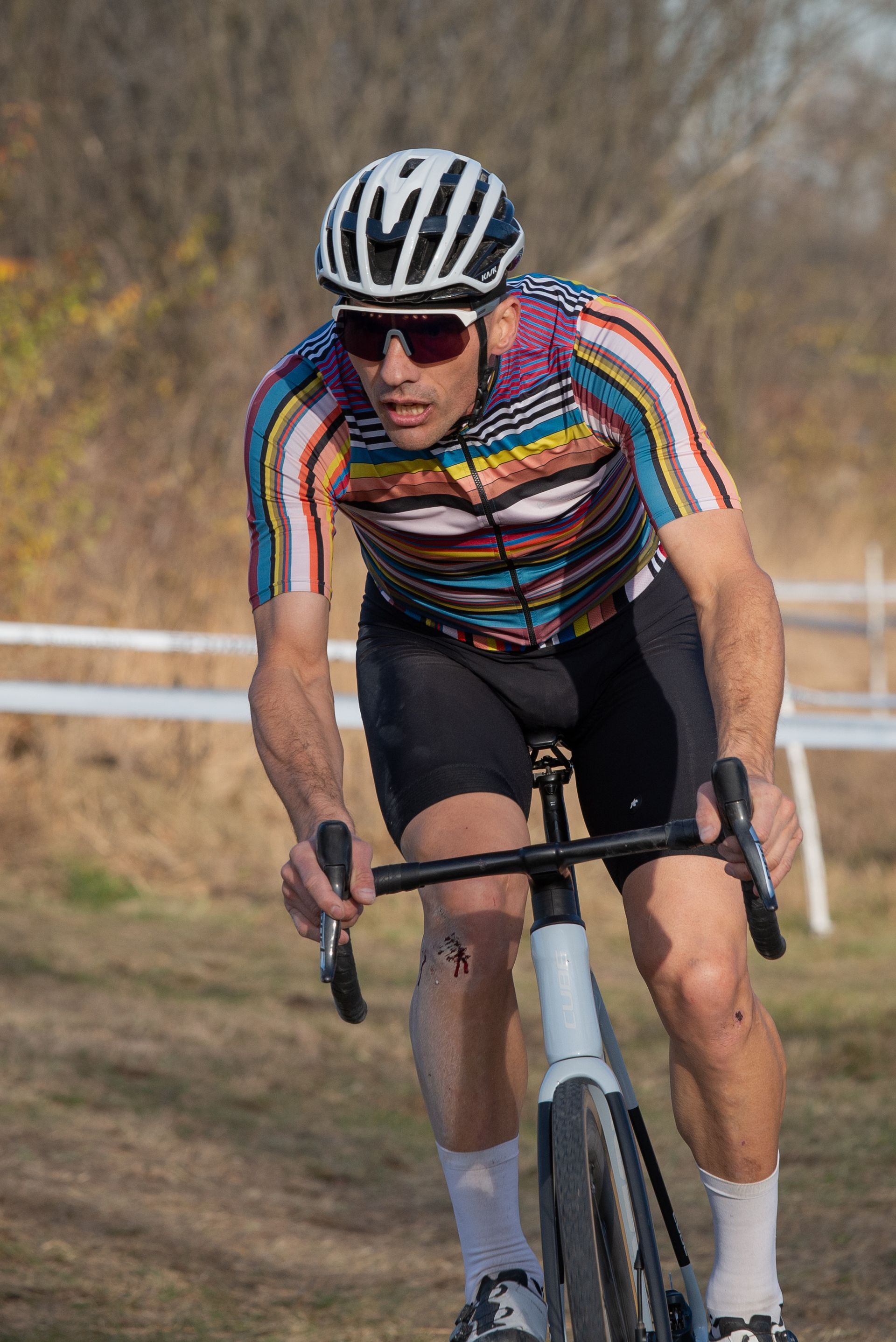 A man wearing a helmet and sunglasses is riding a bike on a dirt road.
