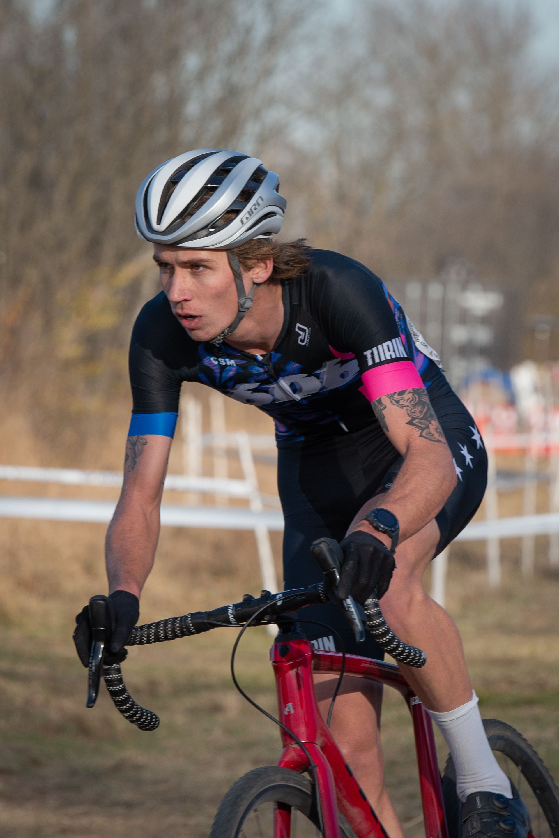 A man wearing a helmet is riding a bicycle on a dirt road.