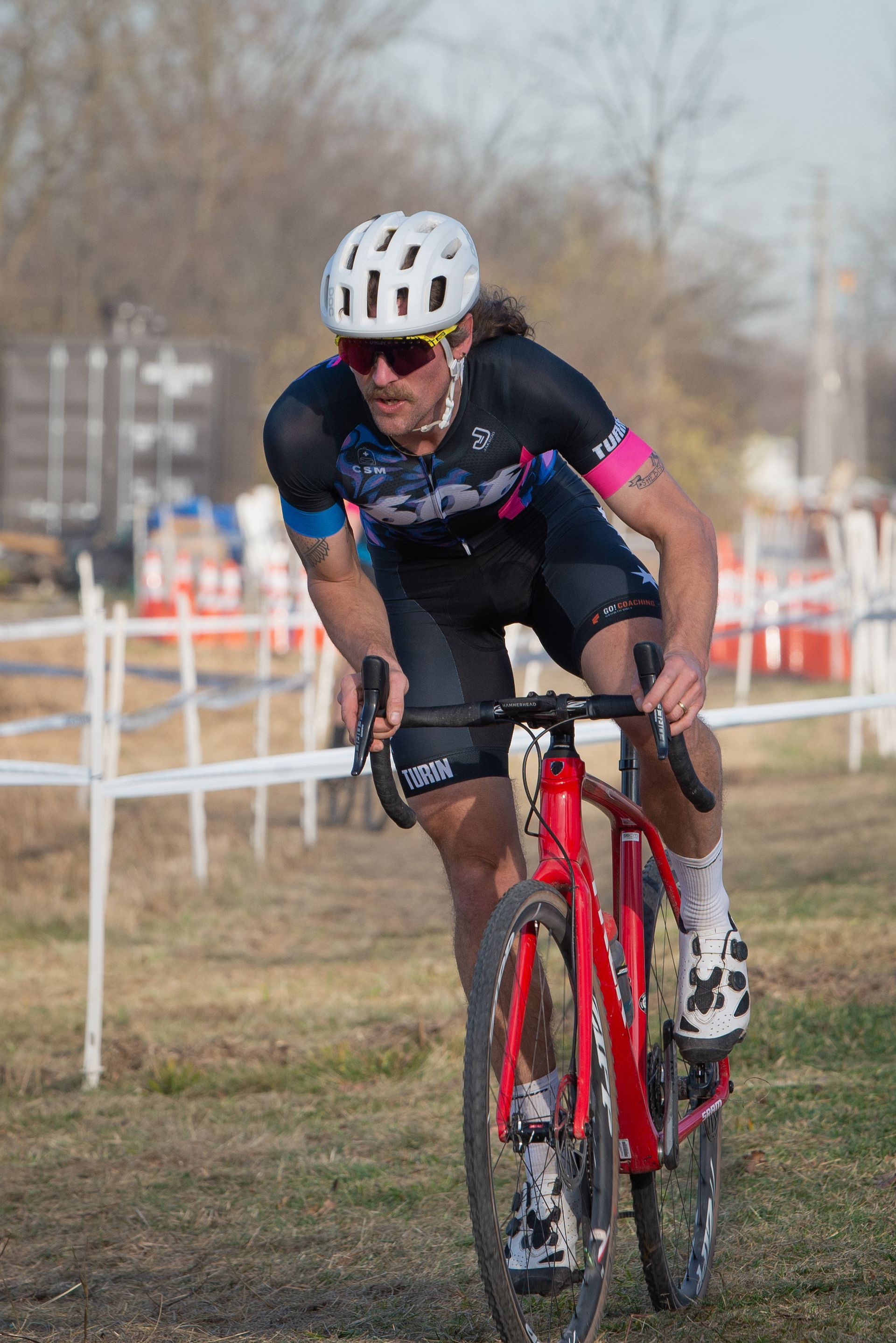 A man is riding a red bicycle on a dirt road.