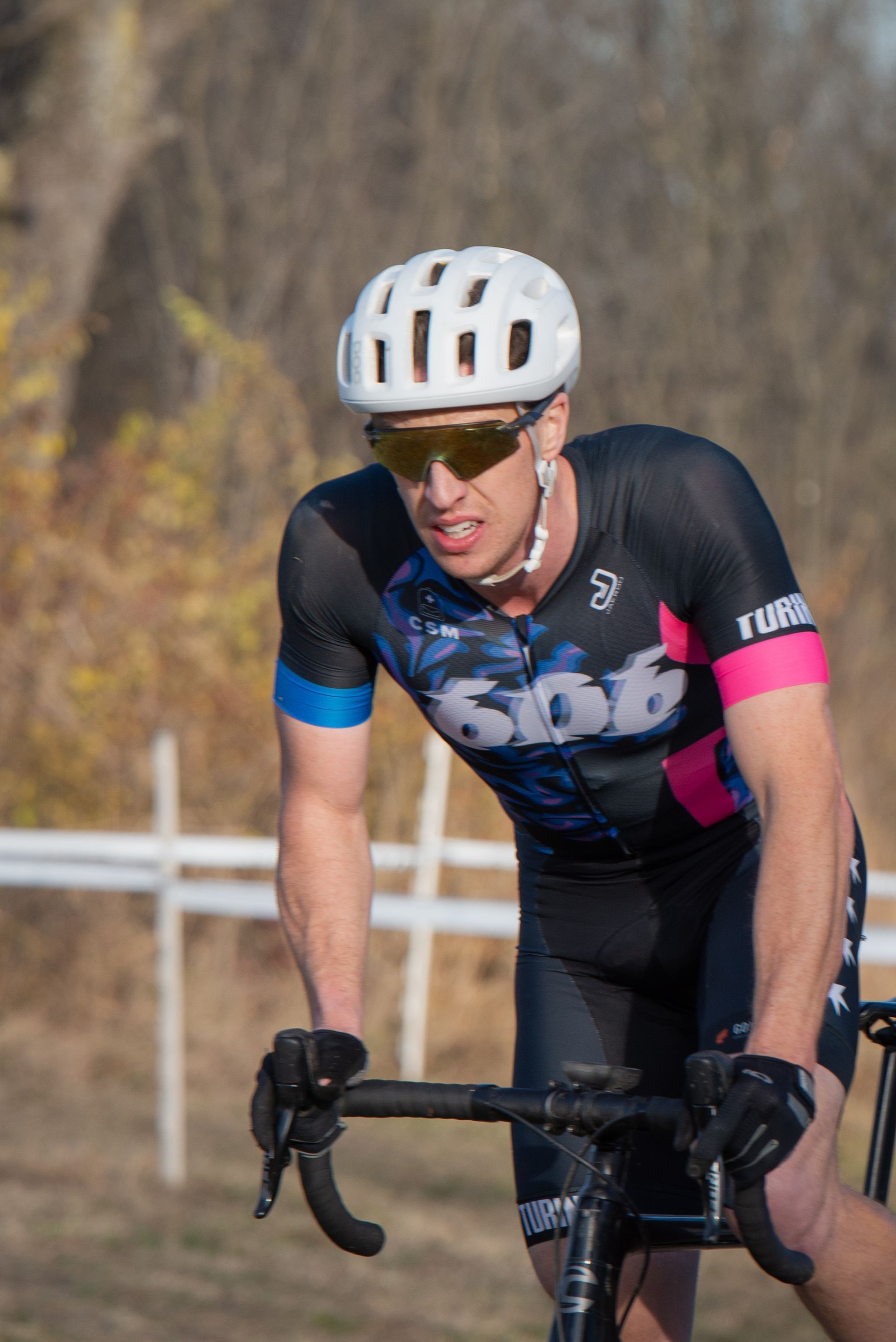 A man wearing a helmet and sunglasses is riding a bike on a dirt road.