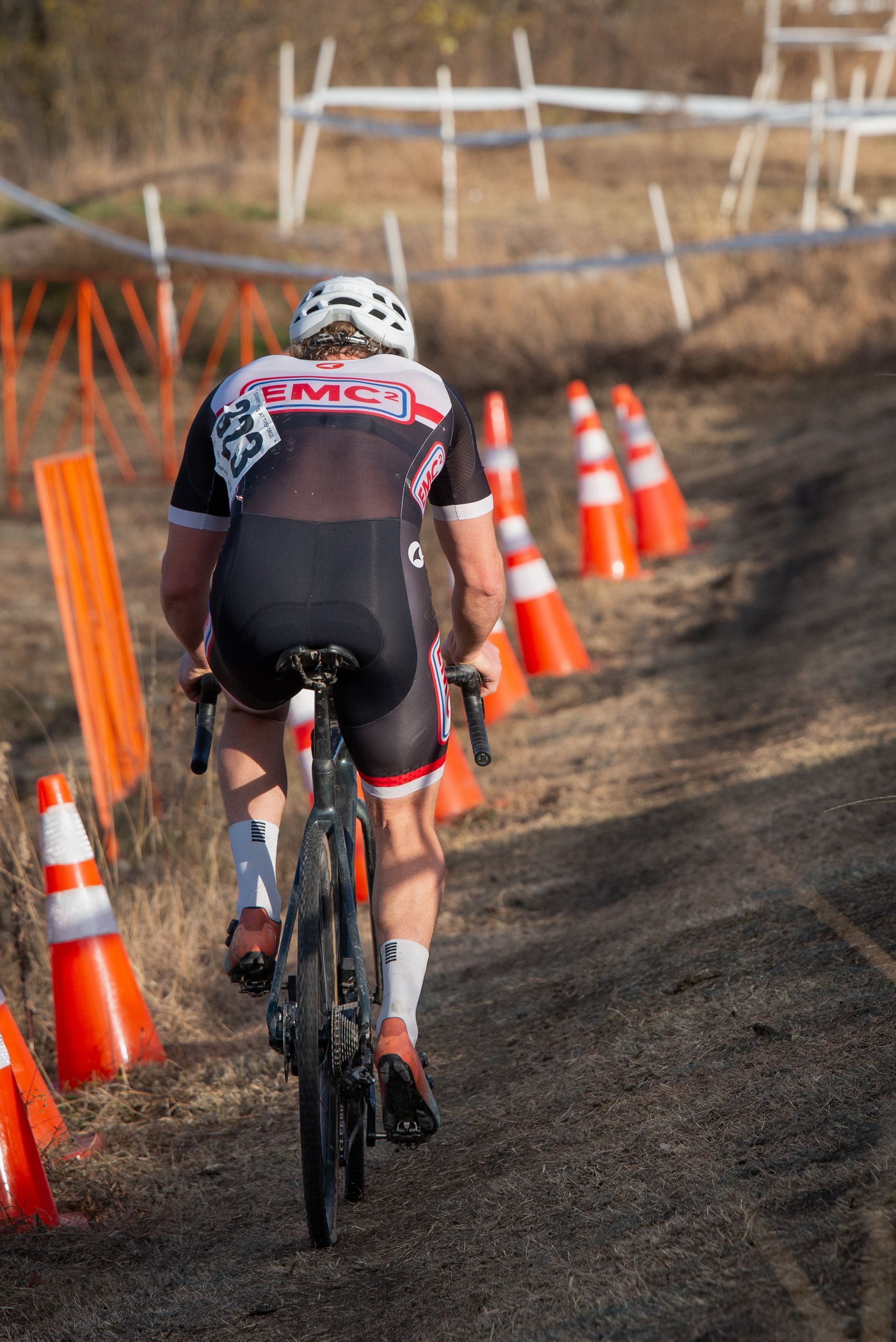 A man is riding a bike down a dirt road surrounded by traffic cones.