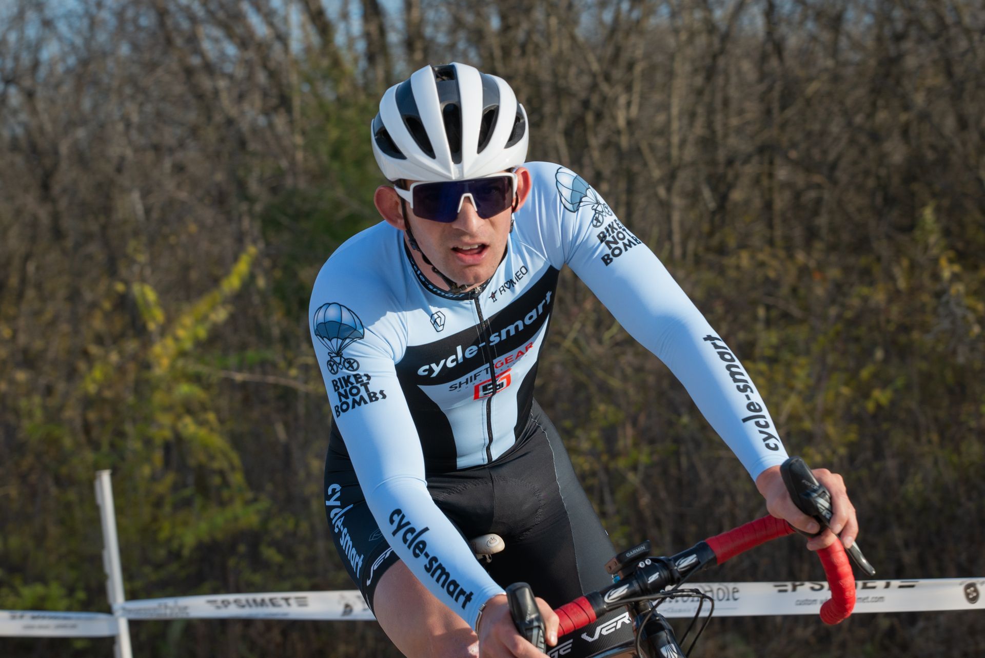 A man wearing a helmet and sunglasses is riding a bike