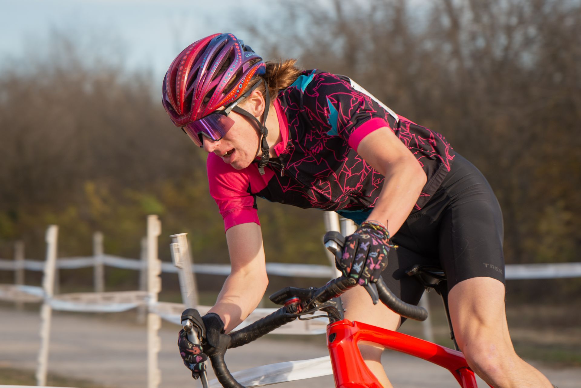 A woman wearing a helmet and sunglasses is riding a bike on a road.