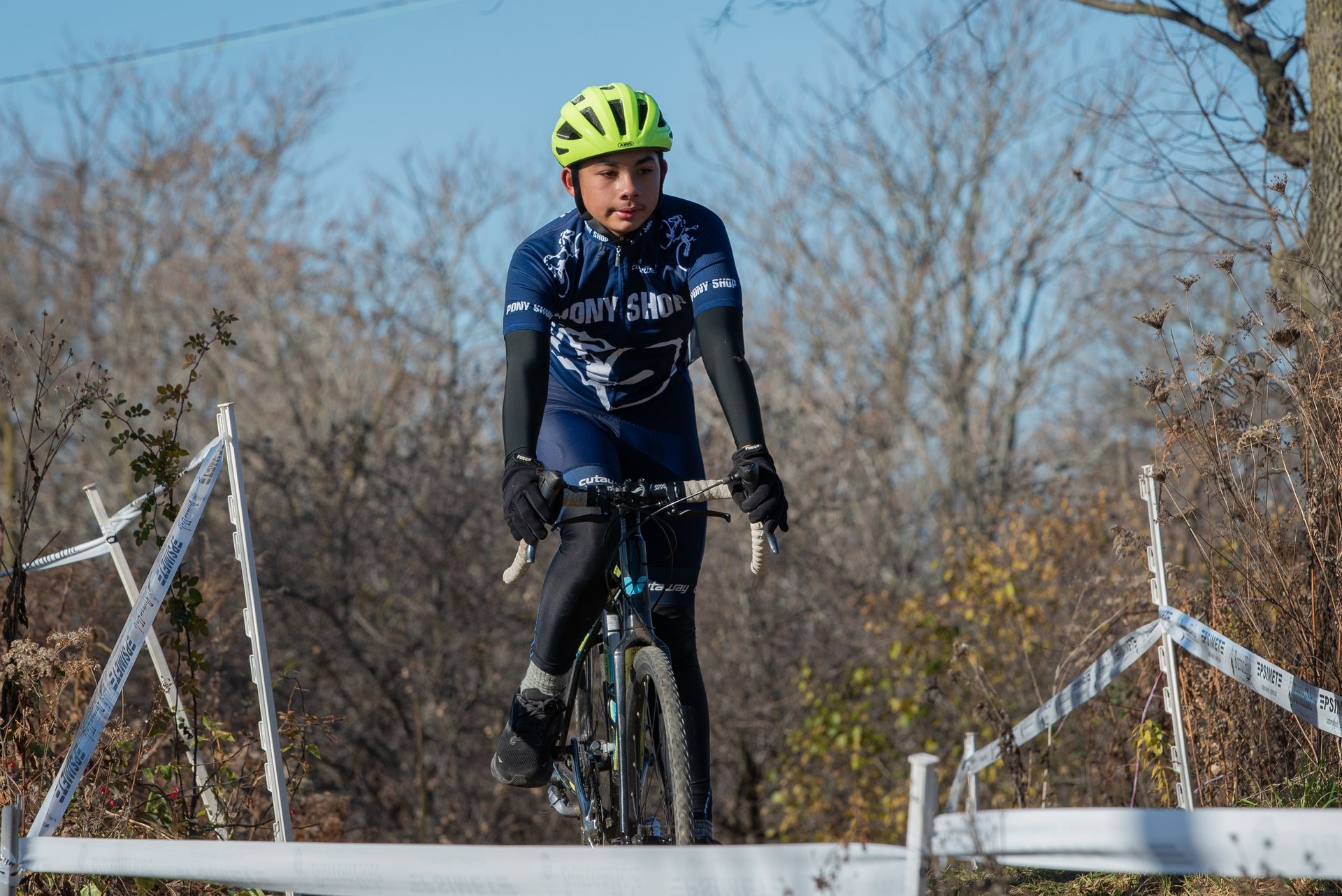 A person wearing a helmet is riding a bike over a fence.