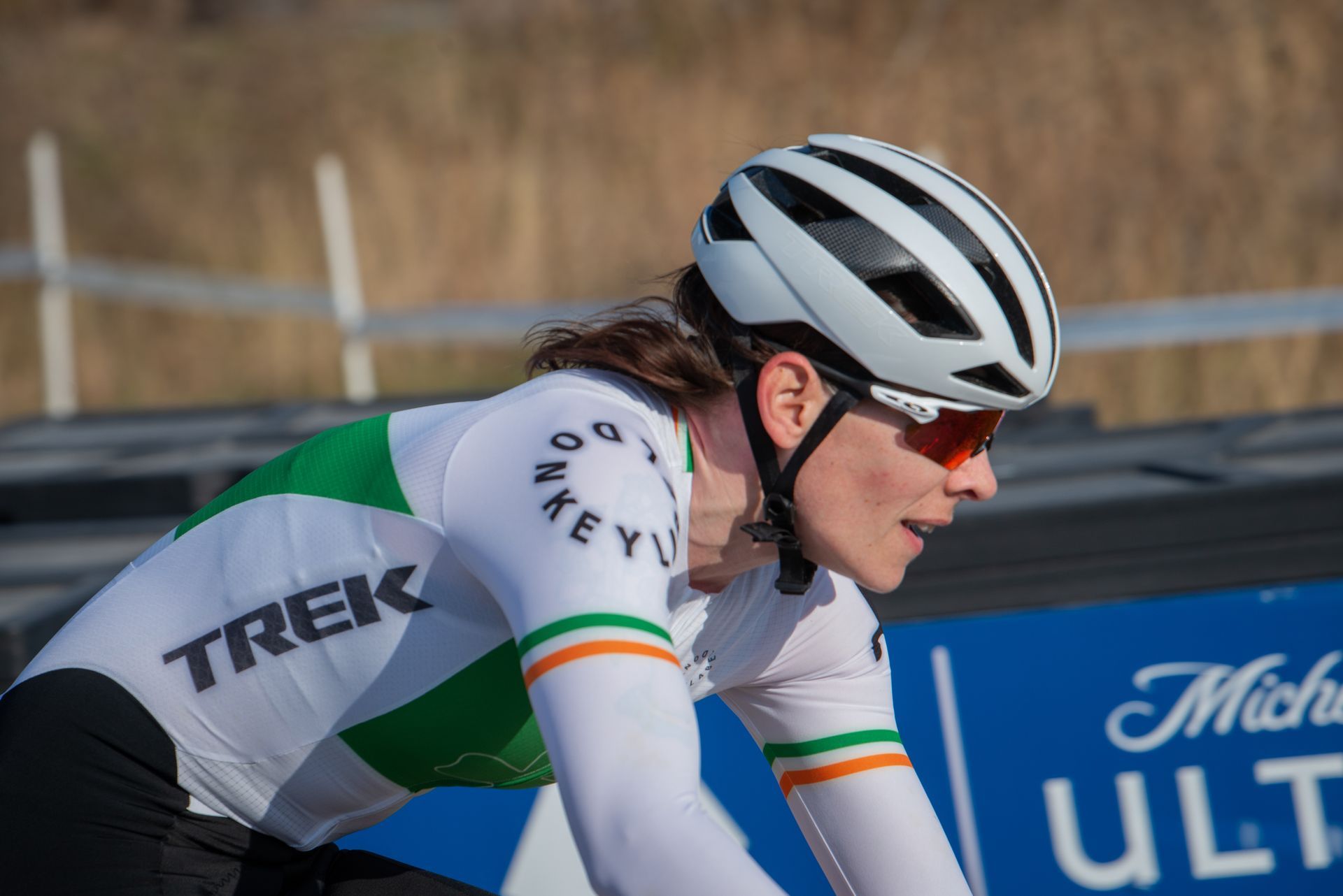 A woman wearing a helmet and sunglasses is riding a bike.