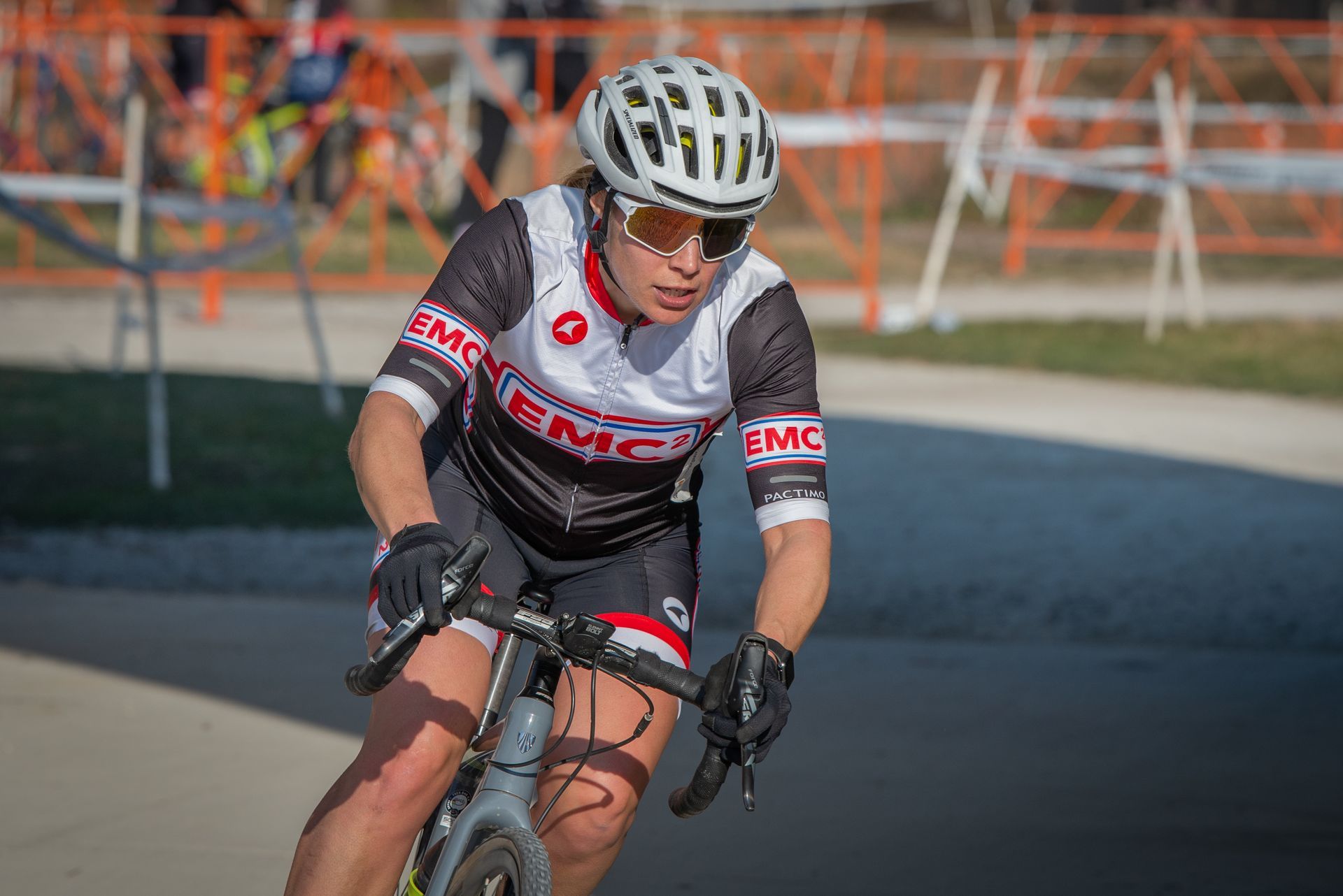 A woman wearing a helmet and sunglasses is riding a bike on a road.
