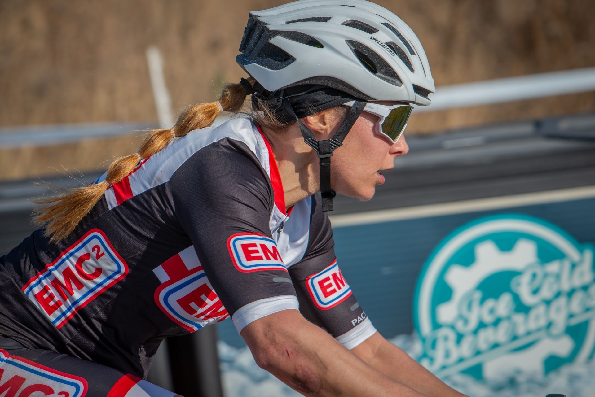 A woman wearing a helmet and sunglasses is riding a bike.