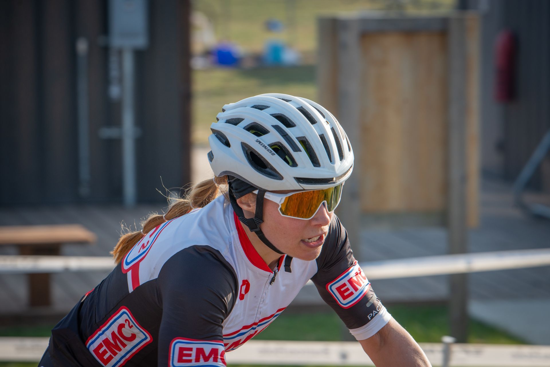 A woman wearing a helmet and sunglasses is riding a bike.