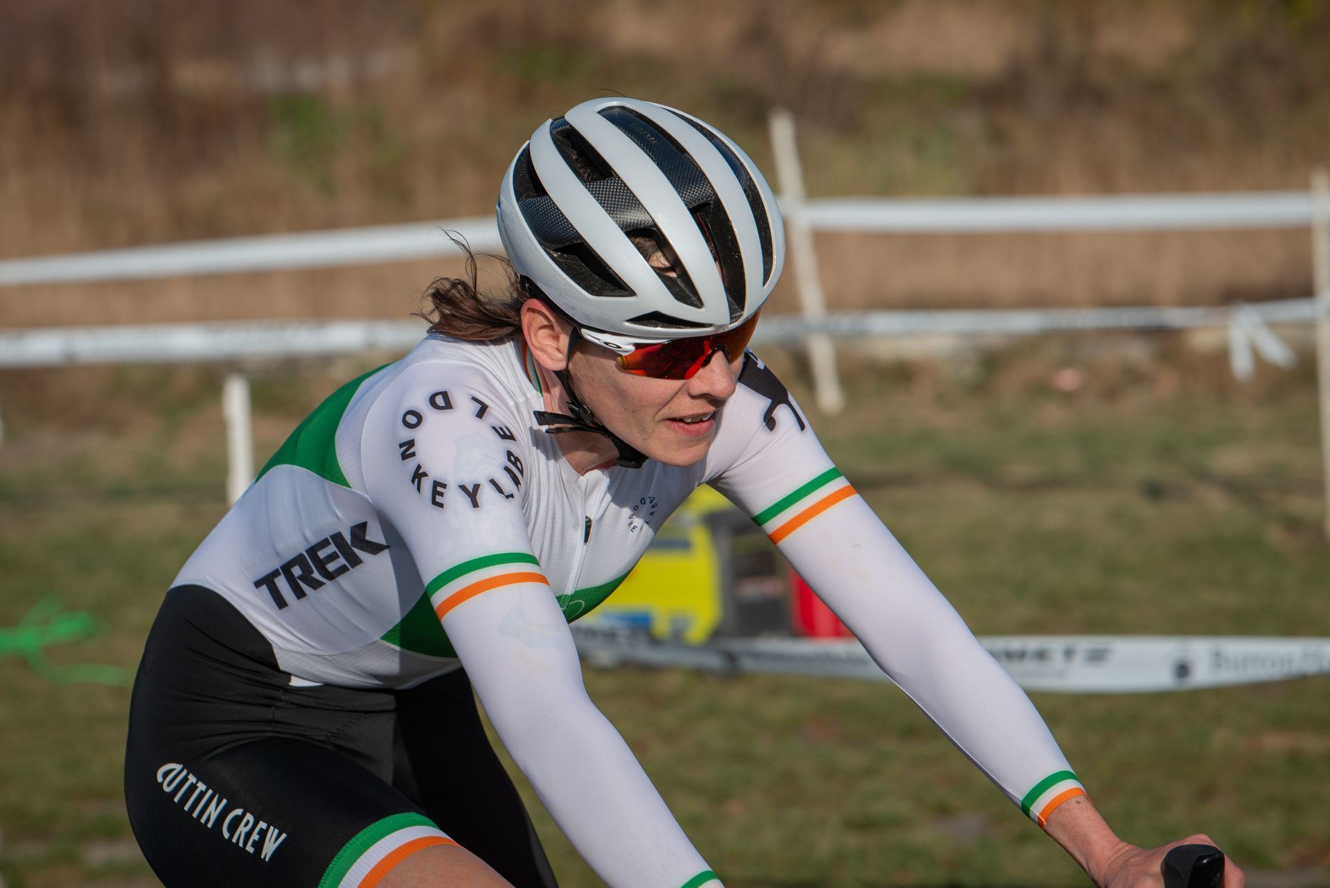 A woman wearing a helmet and sunglasses is riding a bike
