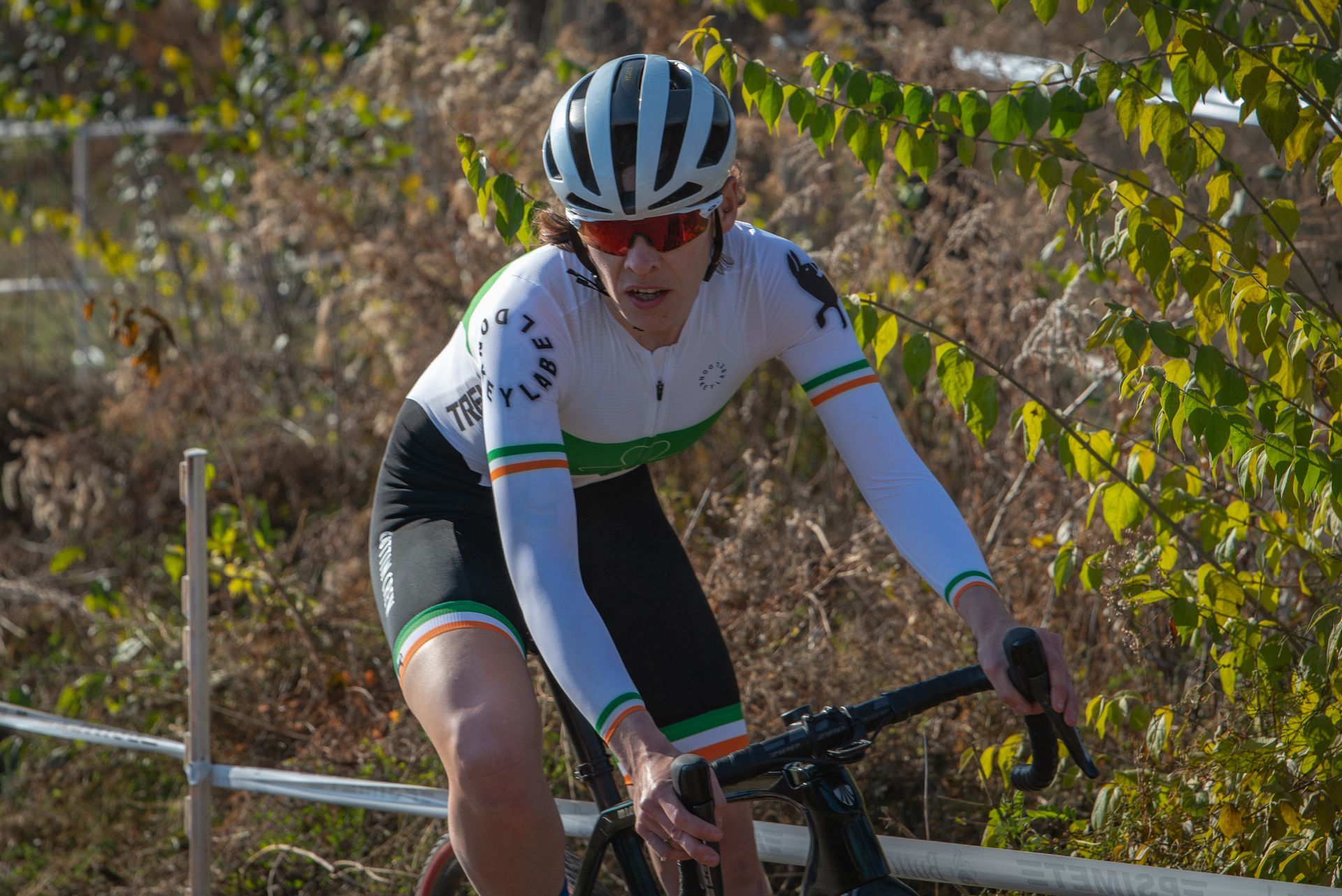 A man wearing a helmet and sunglasses is riding a bike.